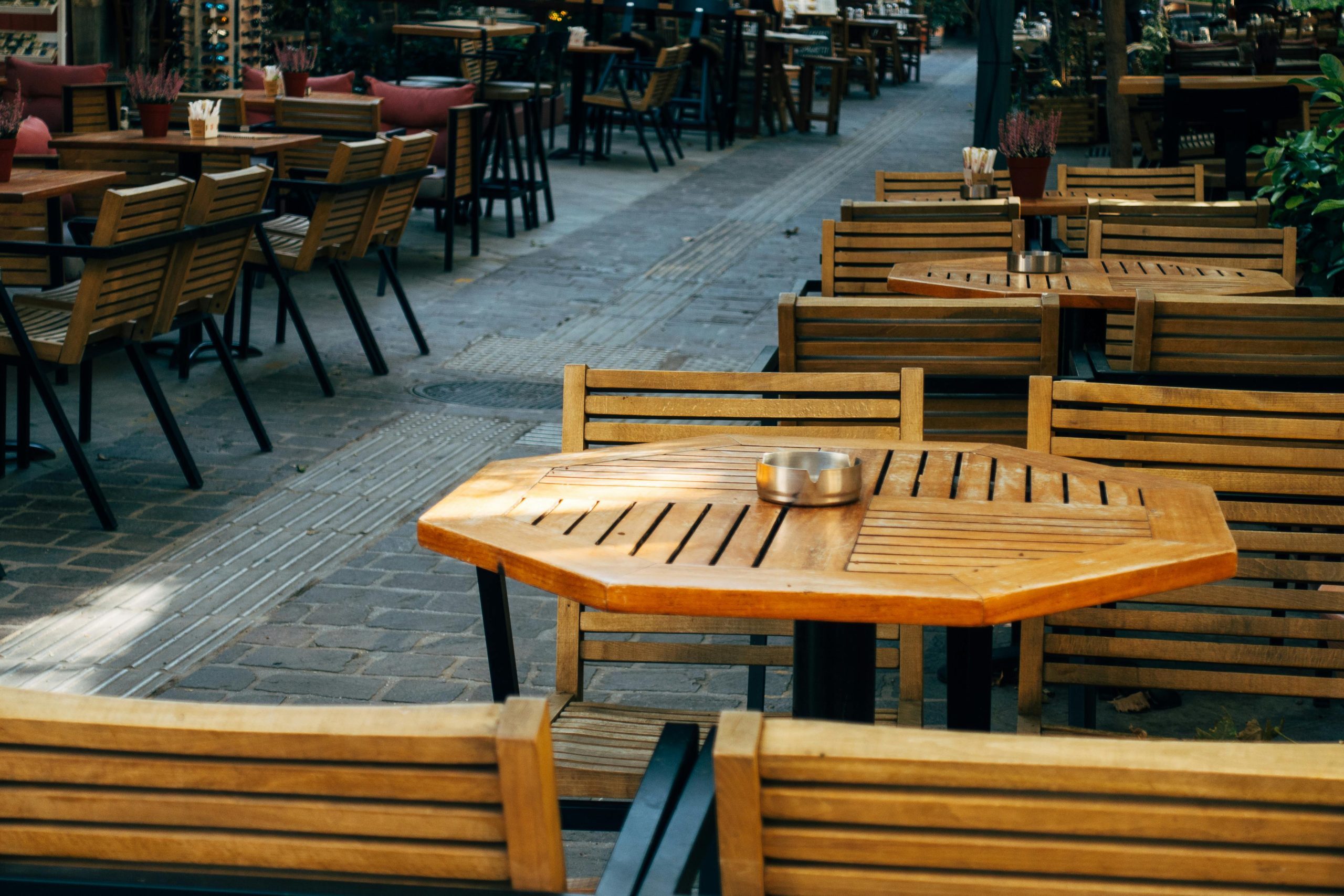 A cozy outdoor café scene with wooden tables and chairs, perfect for dining or coffee.