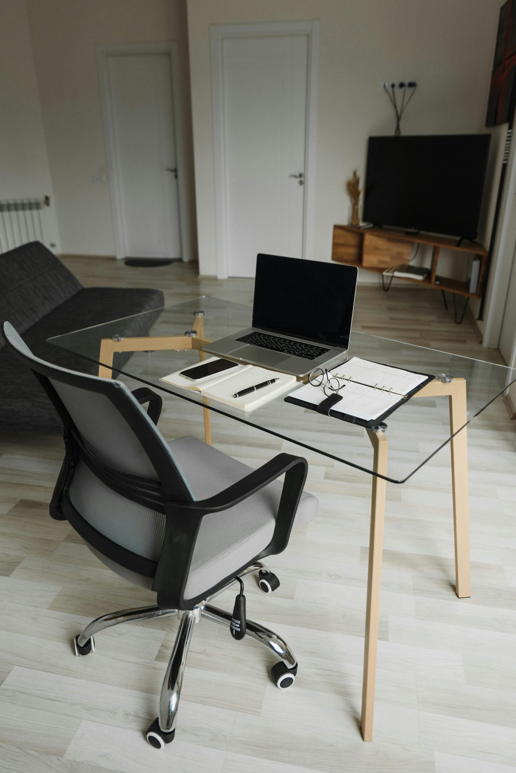 A sleek home office with glass desk and laptop, perfect for remote work inspiration.