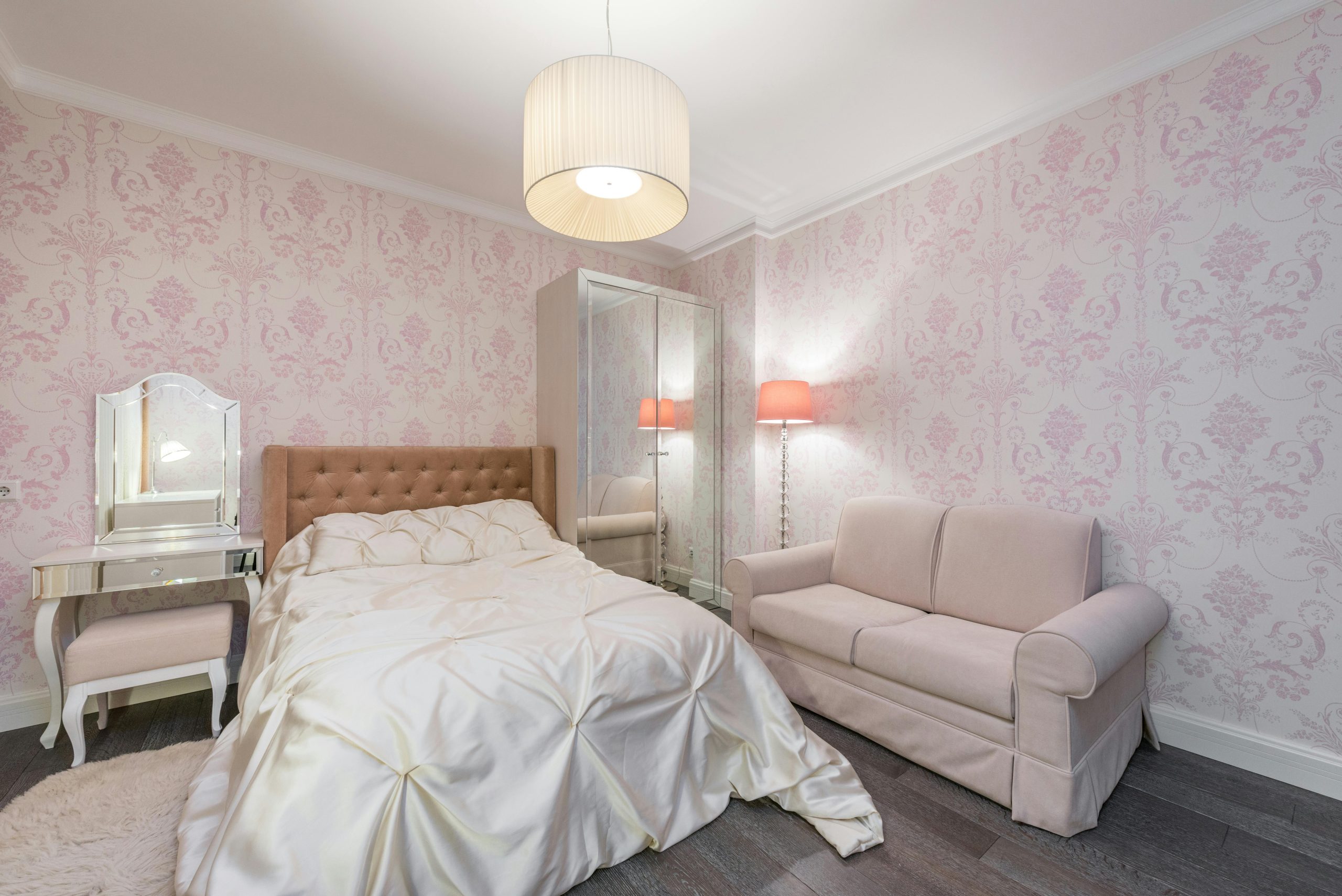 A stylish bedroom featuring pink wallpaper, a comfortable bed, and elegant decor.