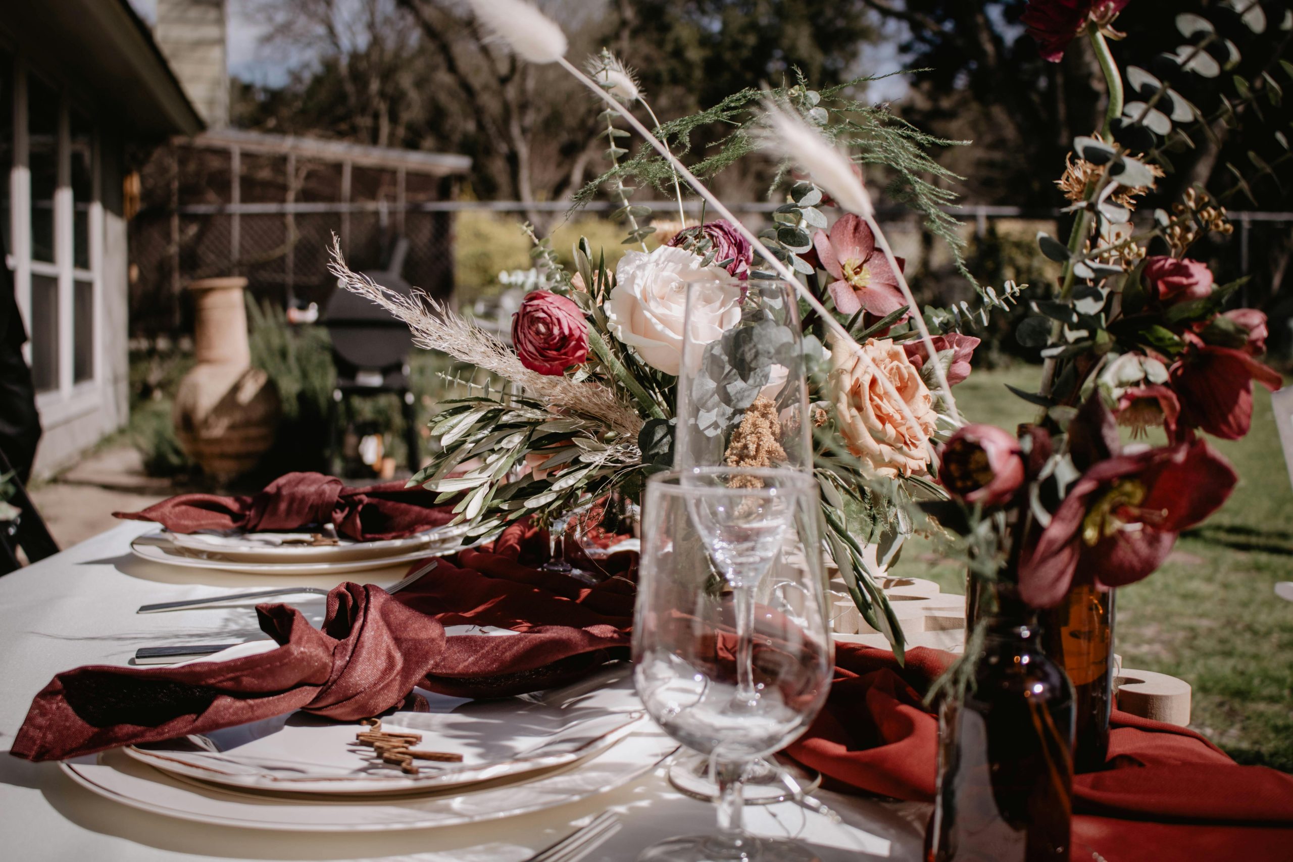 Beautifully arranged outdoor dining table with floral decoration and tableware, perfect for gatherings.