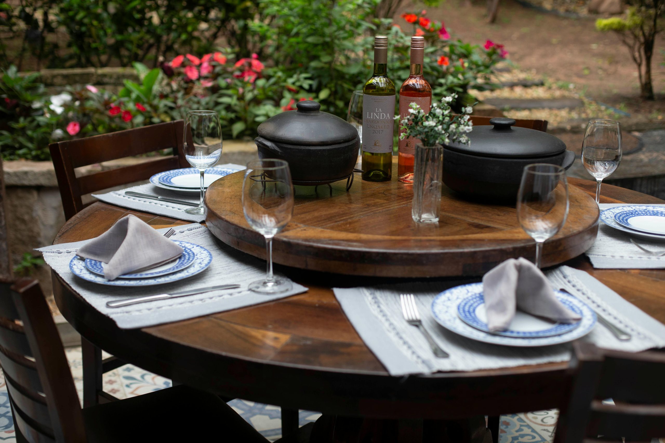 Beautifully set outdoor dining table with wine and floral centerpiece for a perfect alfresco meal.