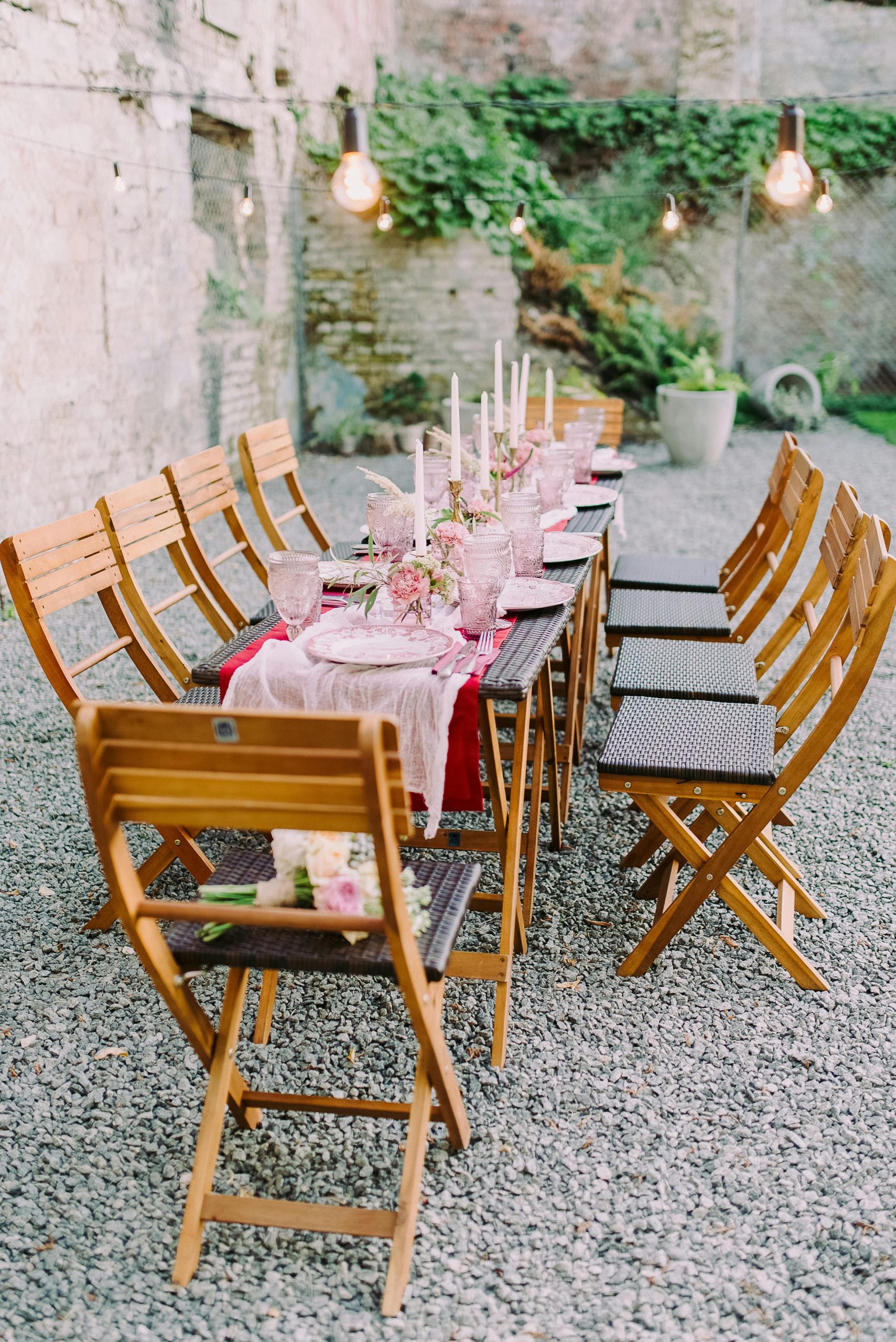 Charming al fresco dining area featuring a beautifully set table with candles and flowers.