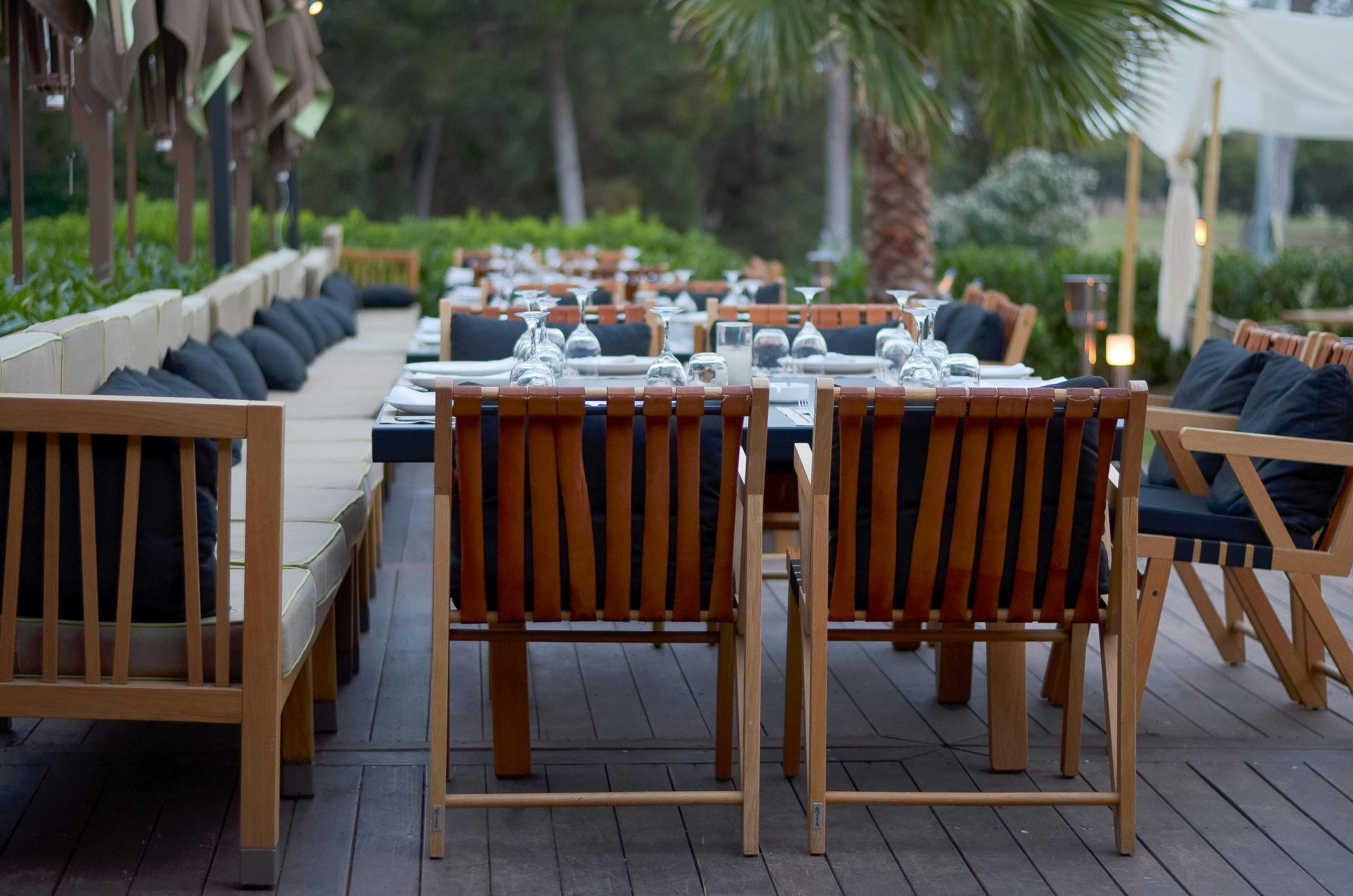 Elegant resort patio with wooden furniture set for outdoor dining in a serene environment.