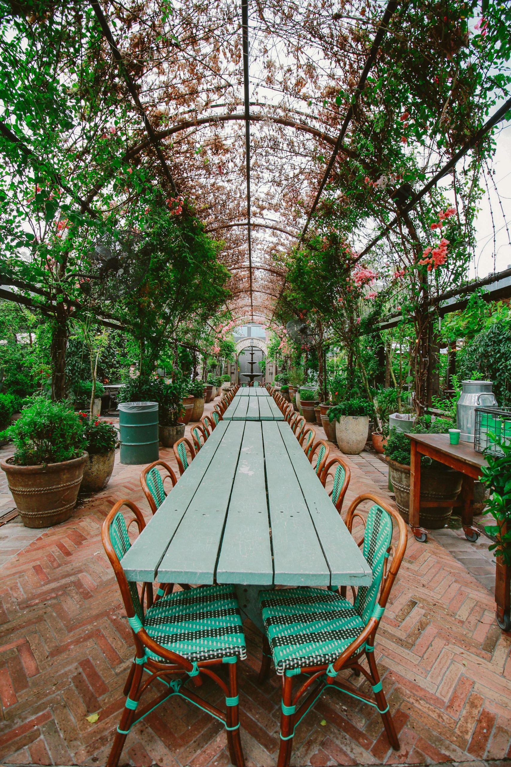 Long table under a lush floral archway, perfect for outdoor dining in a serene garden setting.