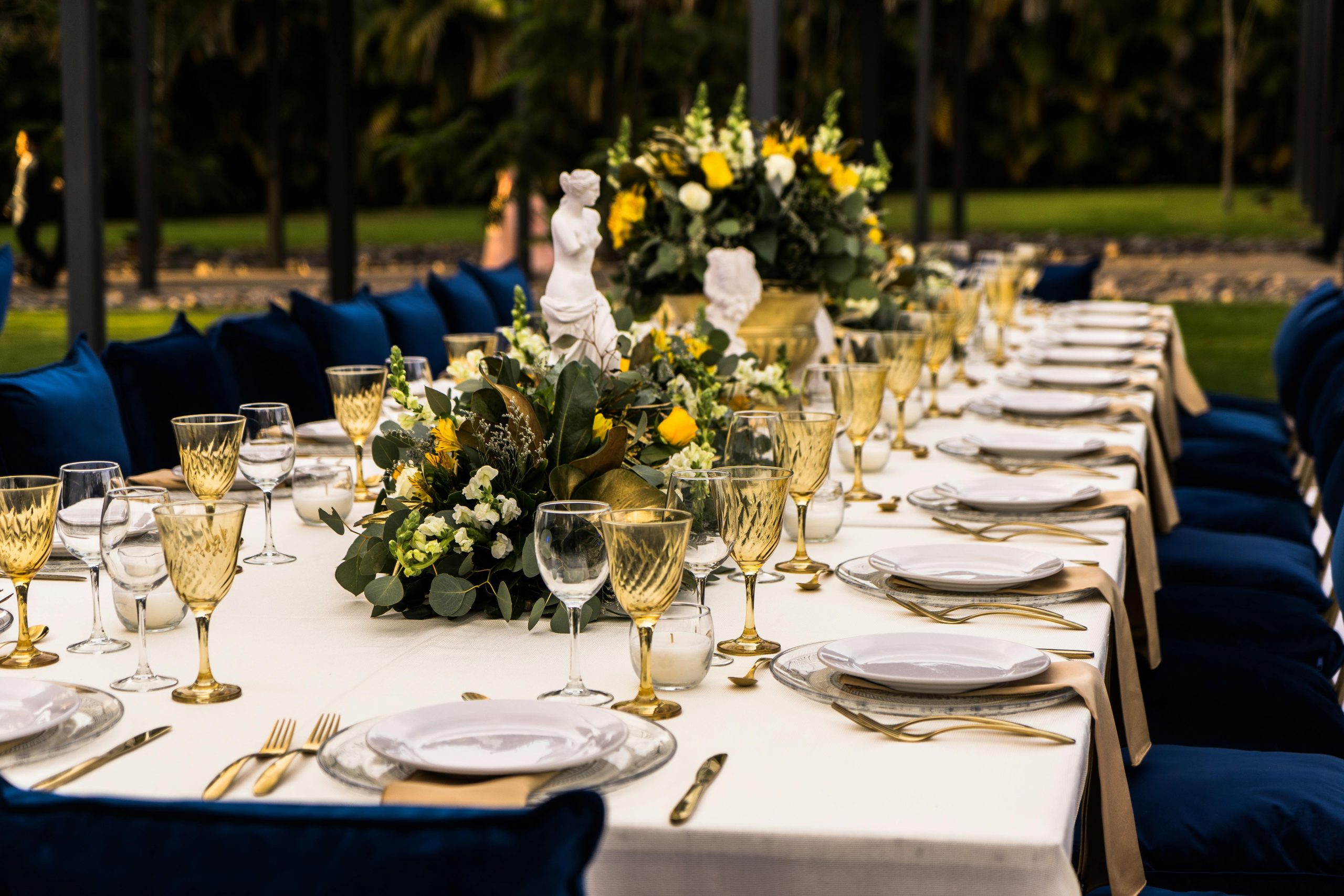 Luxurious outdoor dining setup with flowers and golden glassware for a sophisticated event.