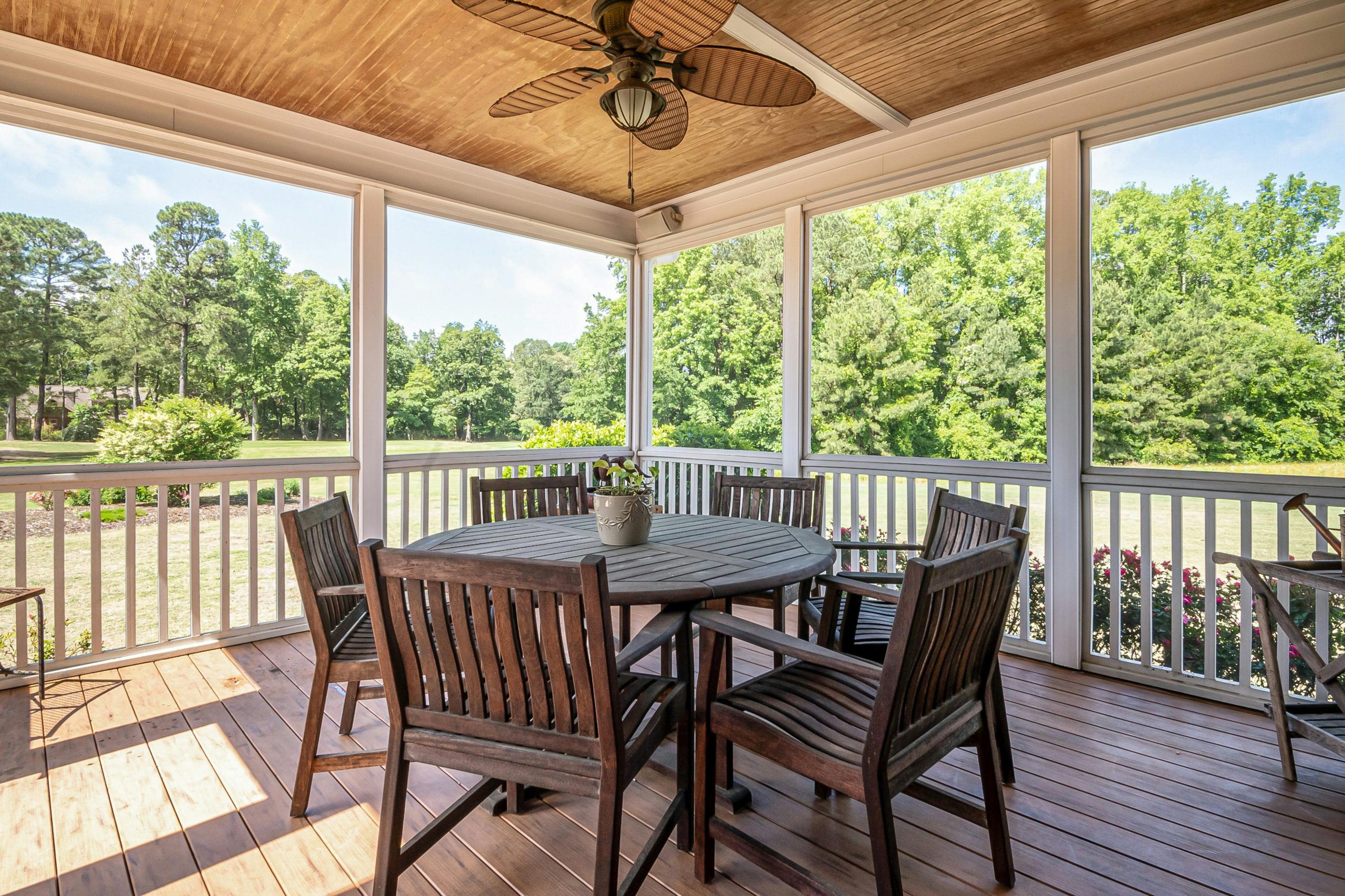 Spacious outdoor patio featuring wooden furniture and scenic garden view, perfect for relaxation.