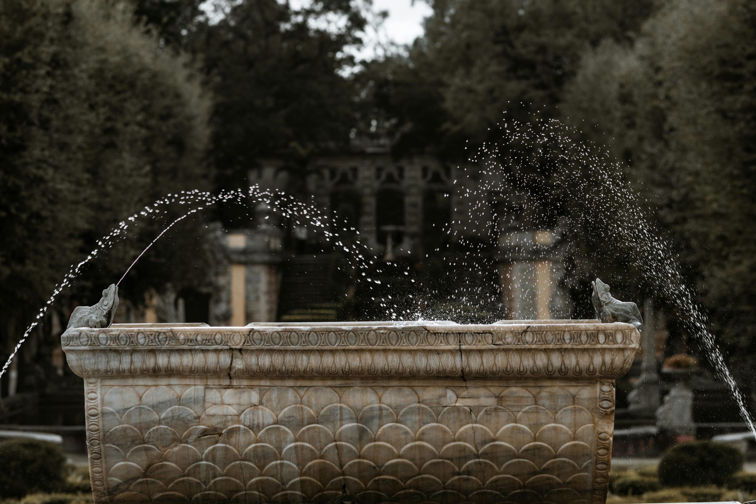 A beautifully crafted stone fountain splashes water in a tranquil garden setting.