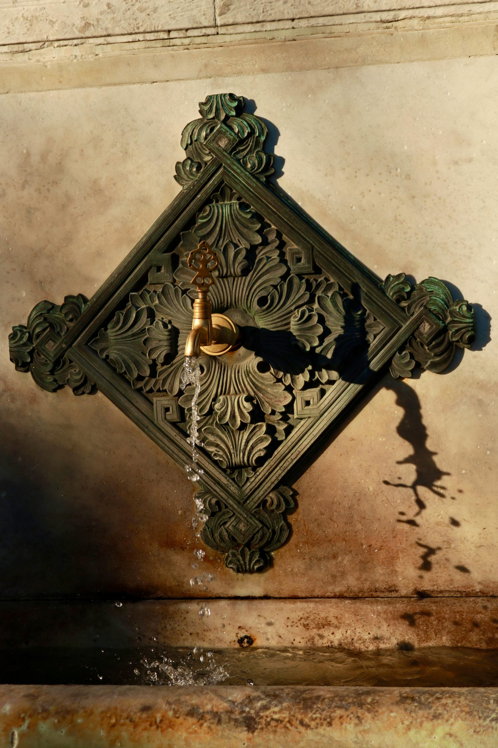 A beautifully ornate vintage wall fountain with intricate design and flowing water.