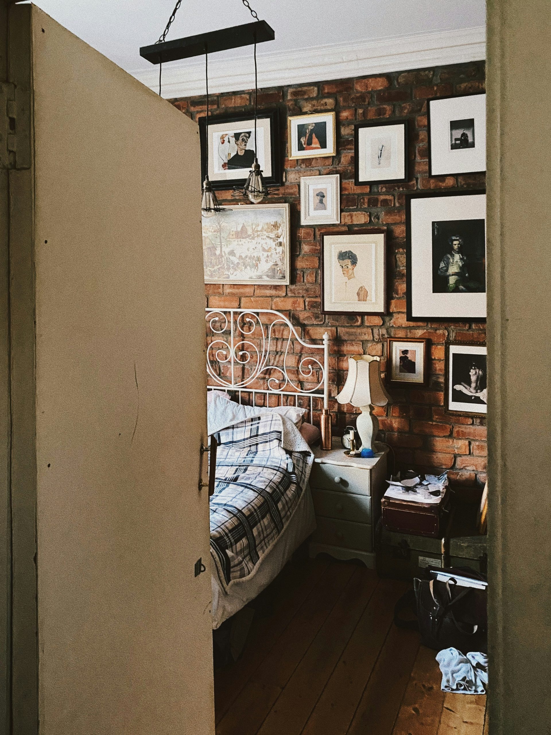 A bedroom with a brick wall and pictures on the wall