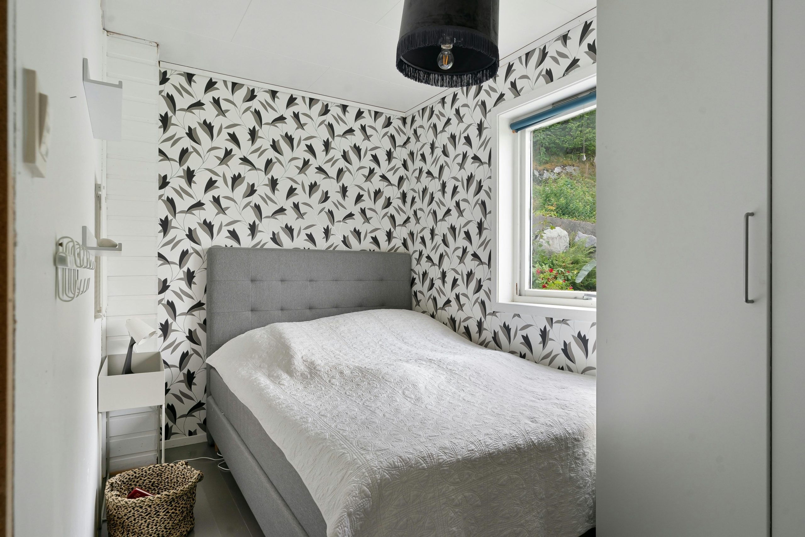 A bright, stylish bedroom featuring modern design elements and a large window overlooking greenery.