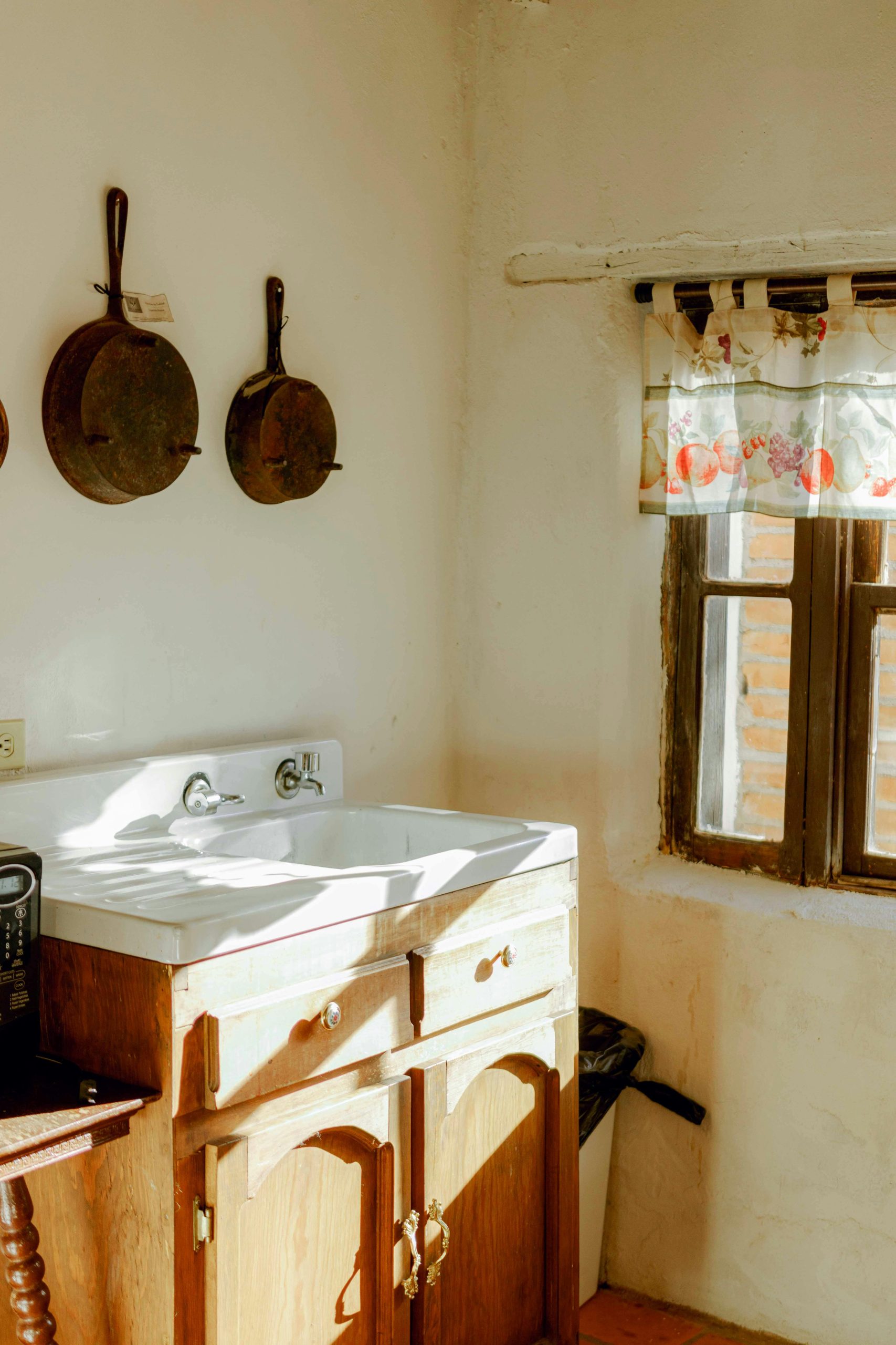 A charming sunlit vintage kitchen corner with a sink and hanging pans, evoking 80s nostalgia.