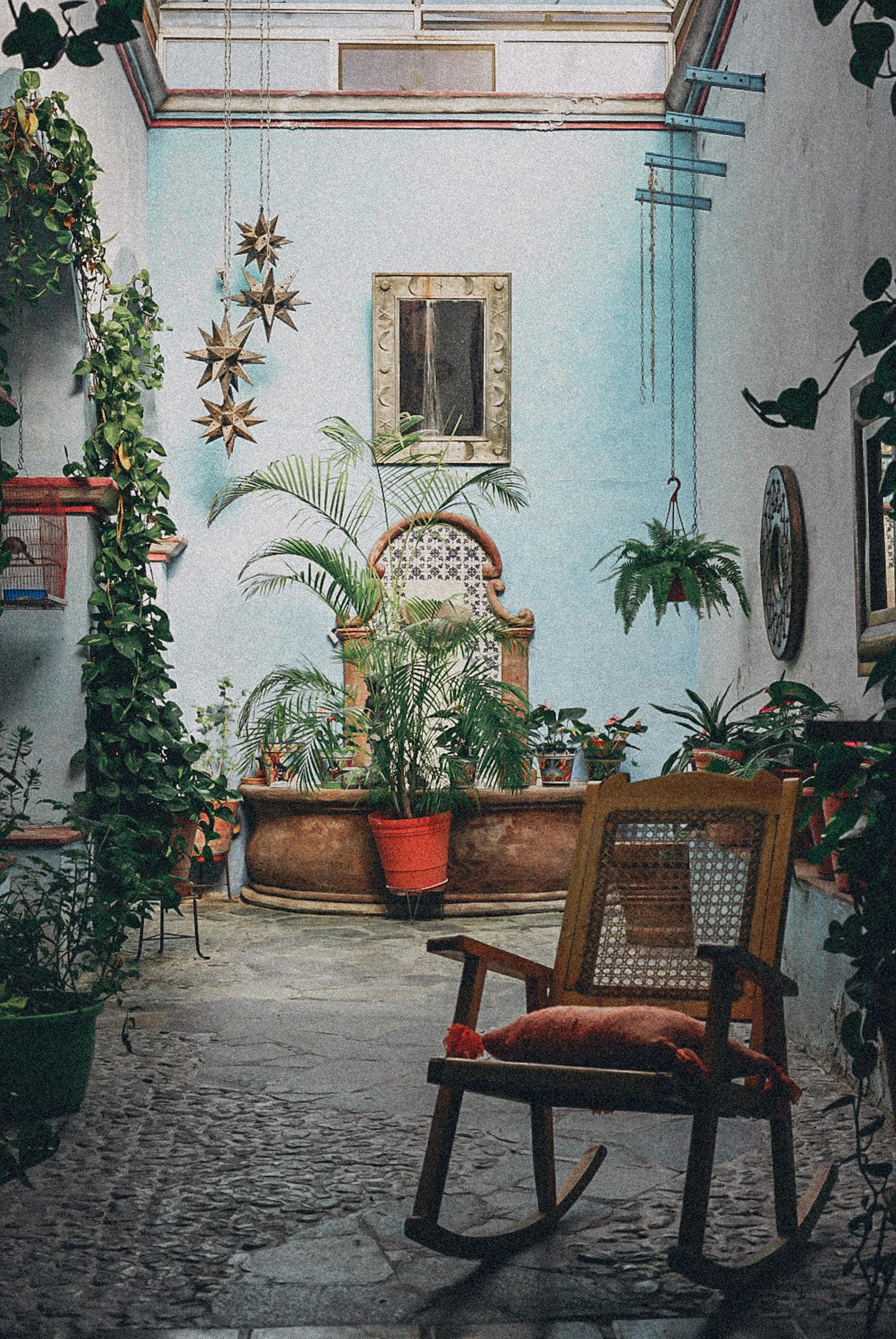 A cozy courtyard in Qro., Mexico featuring plants and a wooden rocking chair.