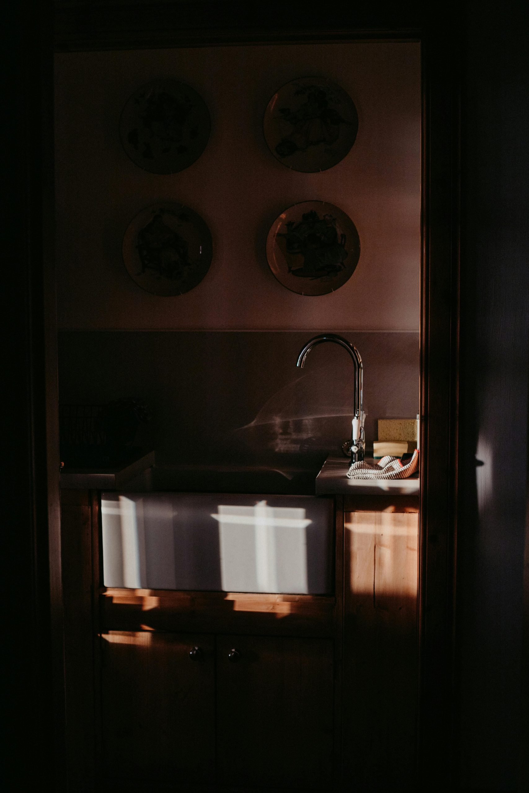A cozy, sunlit kitchen with a farmhouse sink and elegant wall plates in Scotland.