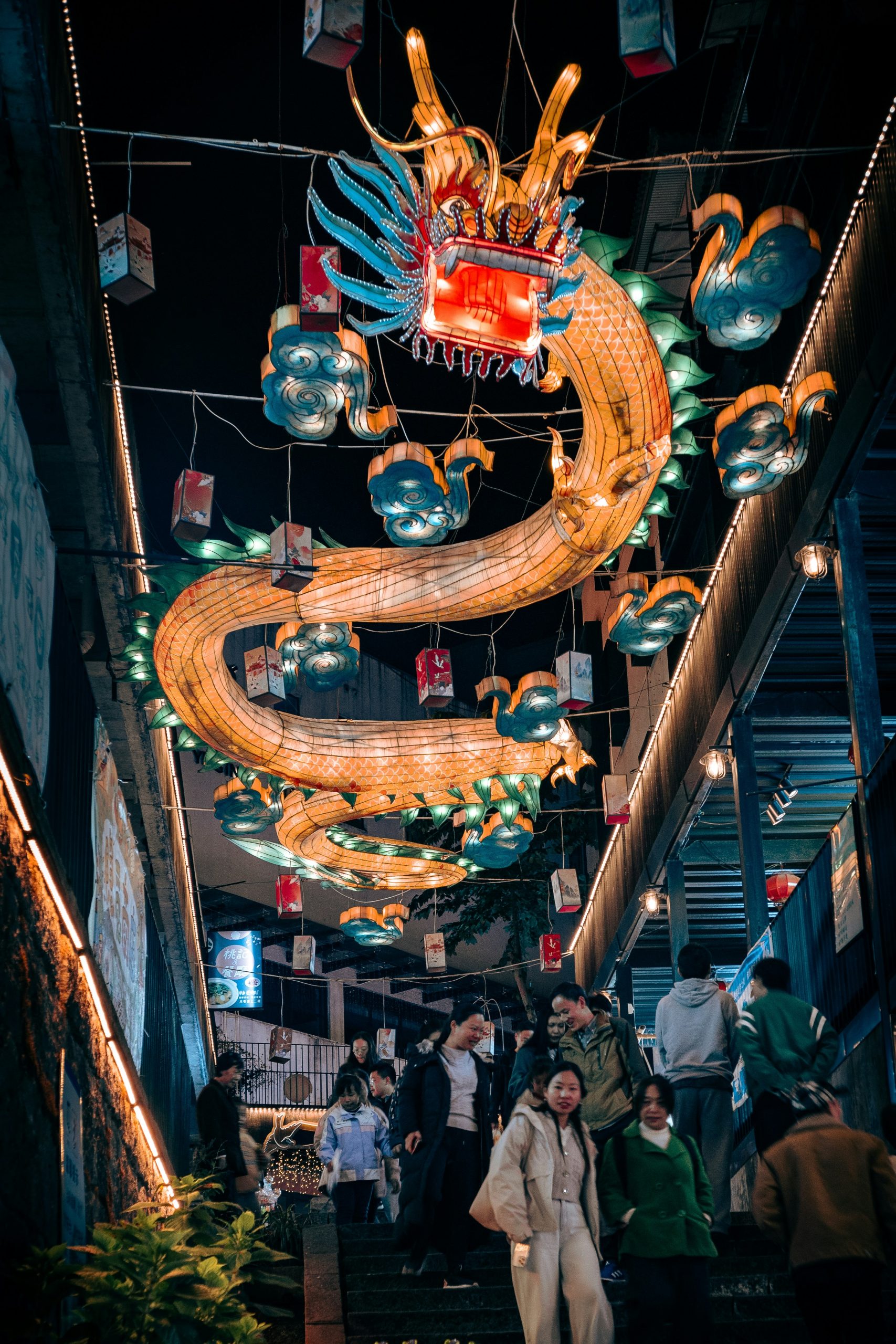 A large illuminated dragon decoration hangs above people on stairs.