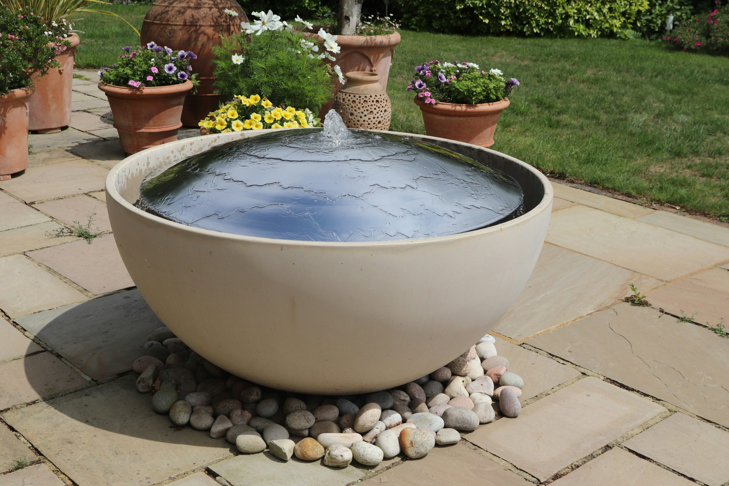 A modern water fountain sits in a garden setting.