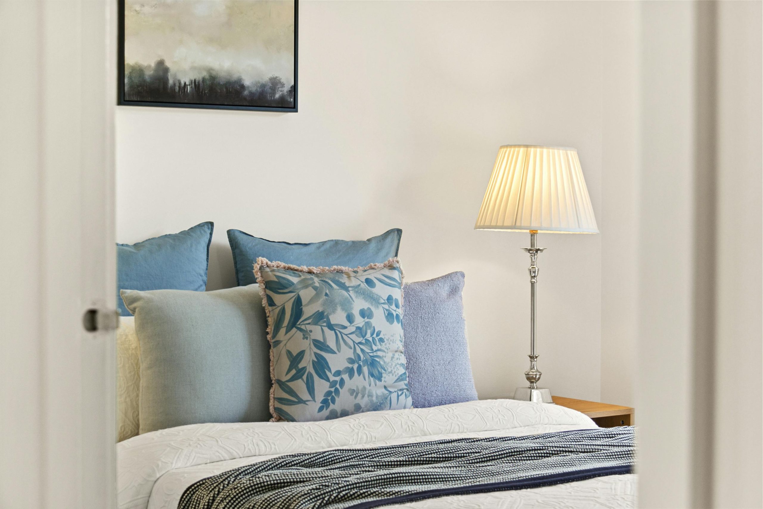 A serene bedroom featuring elegant decor, plush cushions, and soft lamp lighting for a cozy ambiance.