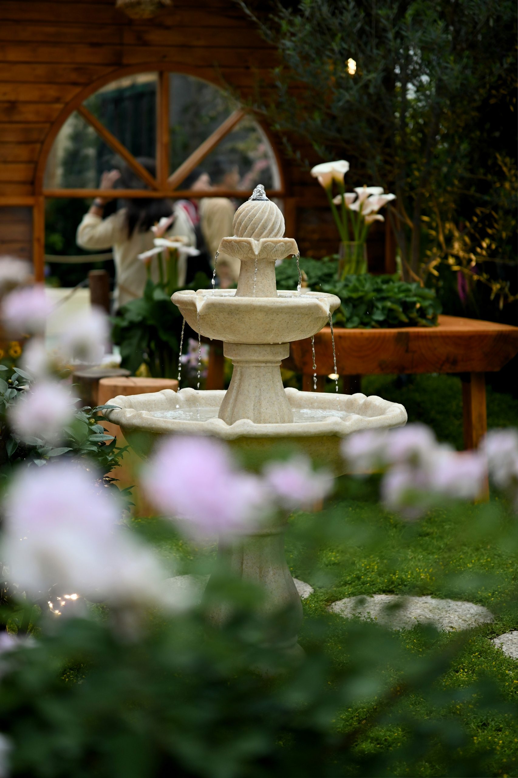 A stone fountain in a garden with flowers.
