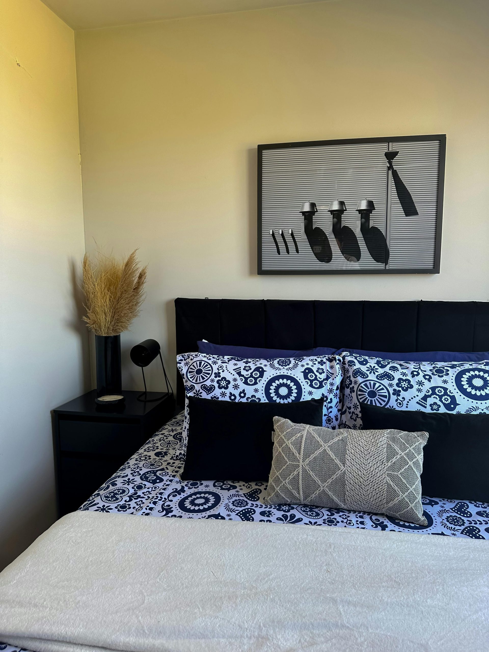 A stylish bedroom with patterned bedding and unique wall art enhances a cozy atmosphere.