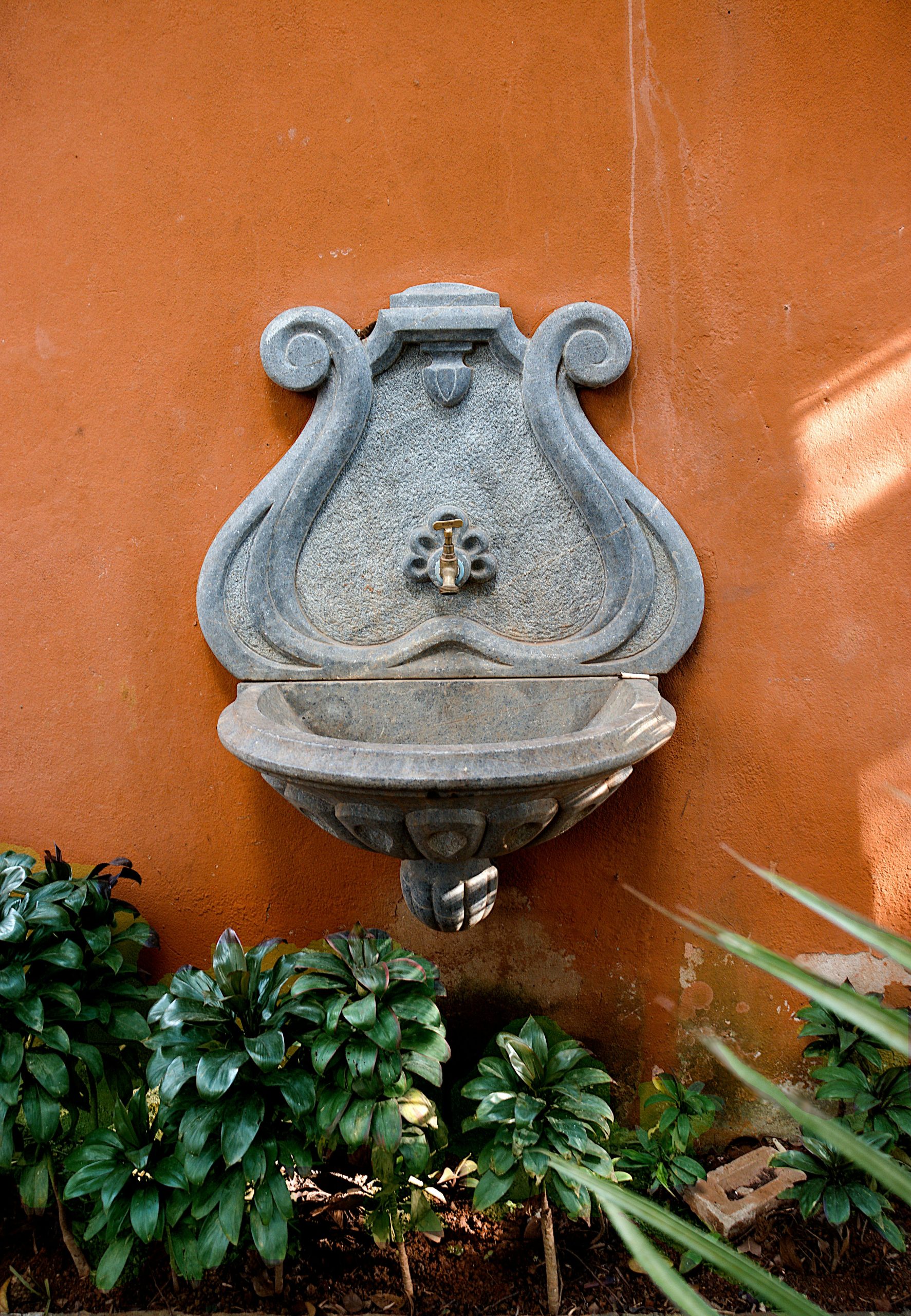 Beautiful ornamental stone fountain against terracotta wall in São Paulo garden.