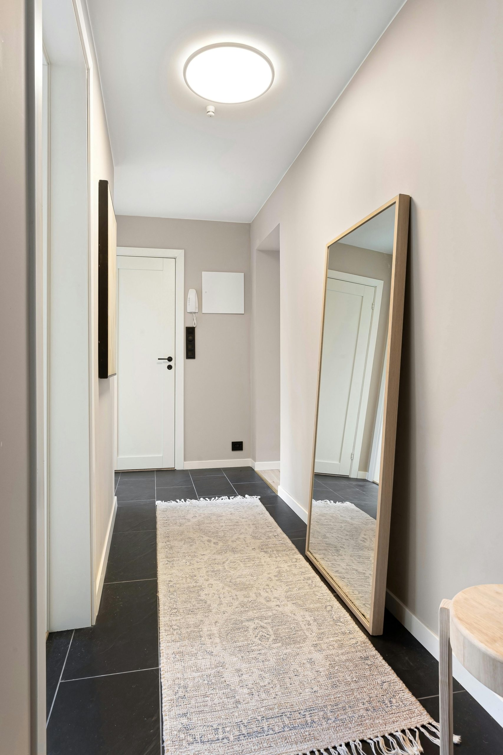 Bright, elegant hallway featuring a large mirror, rug, and simple decor.