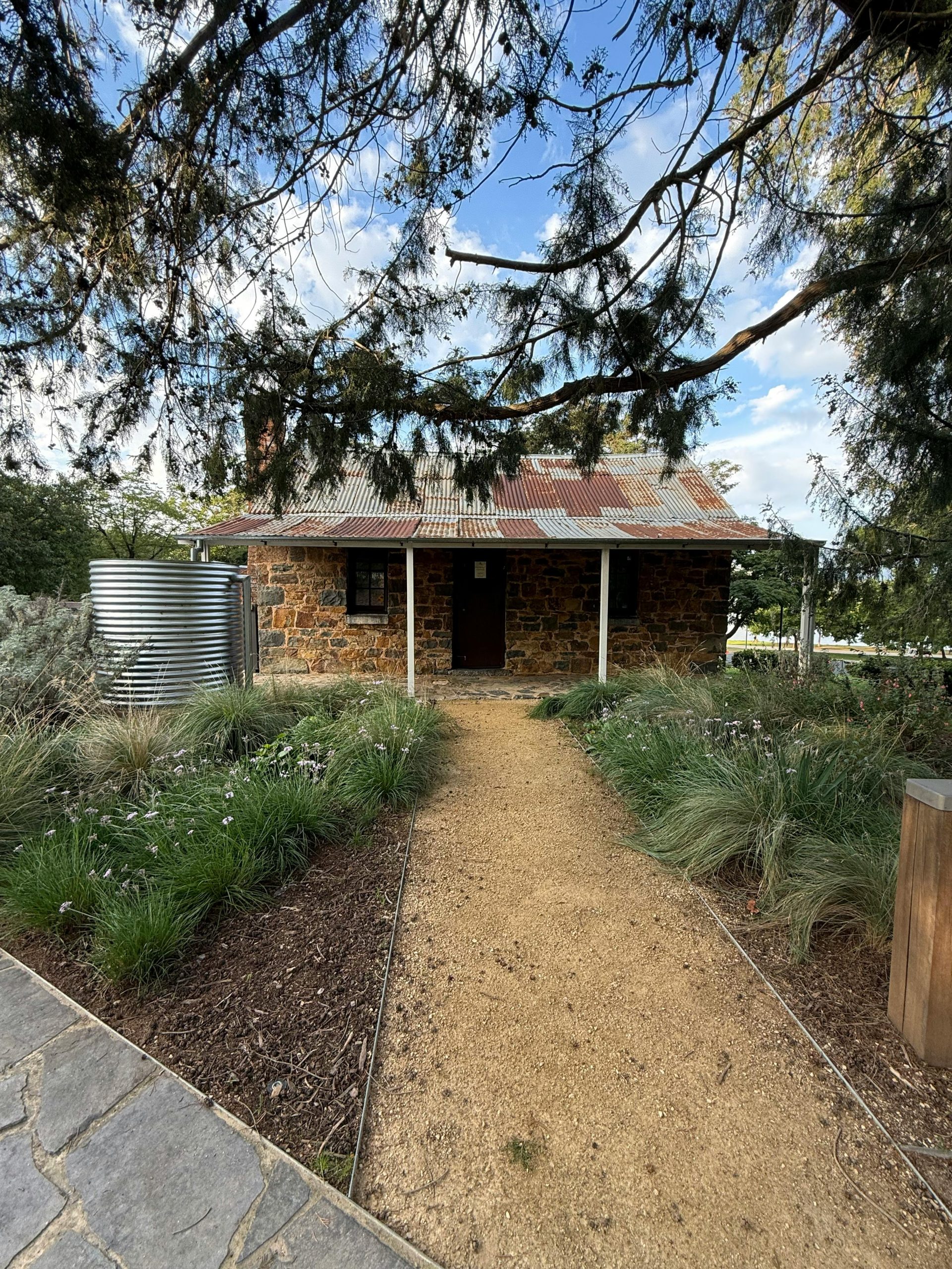 Charming stone cottage surrounded by lush greenery, pathway leads to this quaint retreat.