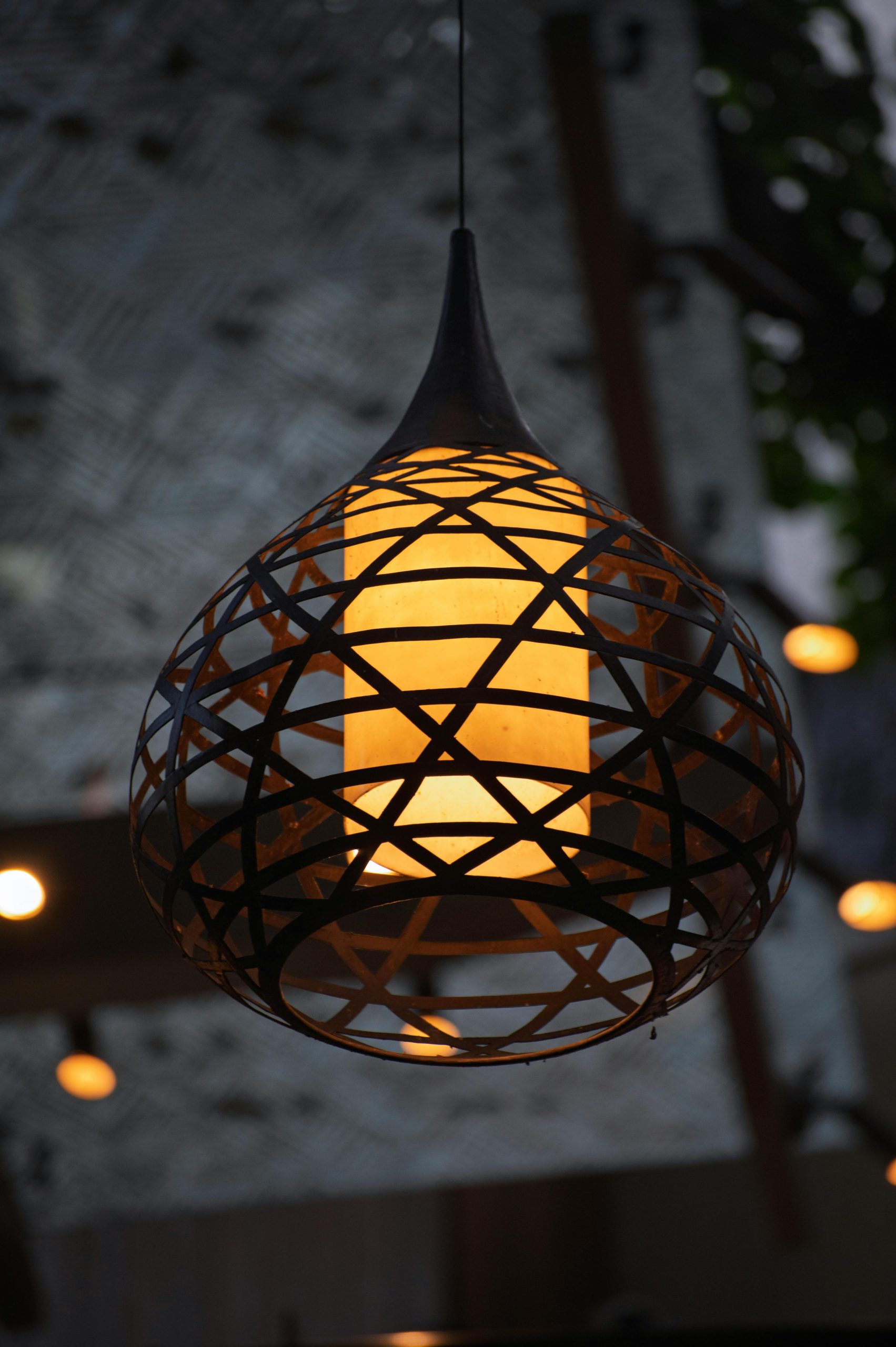 Elegant hanging lantern with a geometric pattern, glowing warmly indoors.