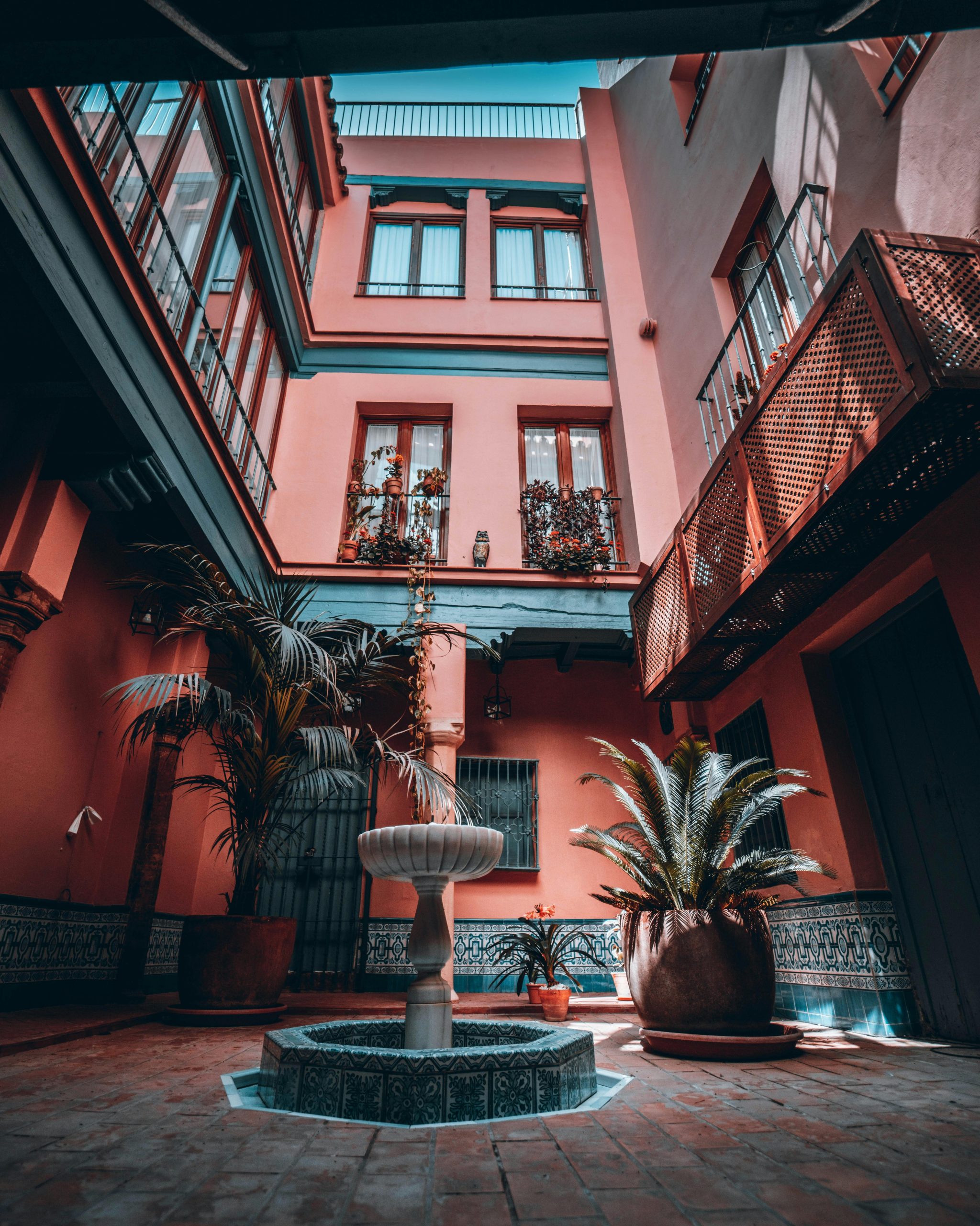 Explore a charming courtyard in Seville with a central fountain and lush palm trees.