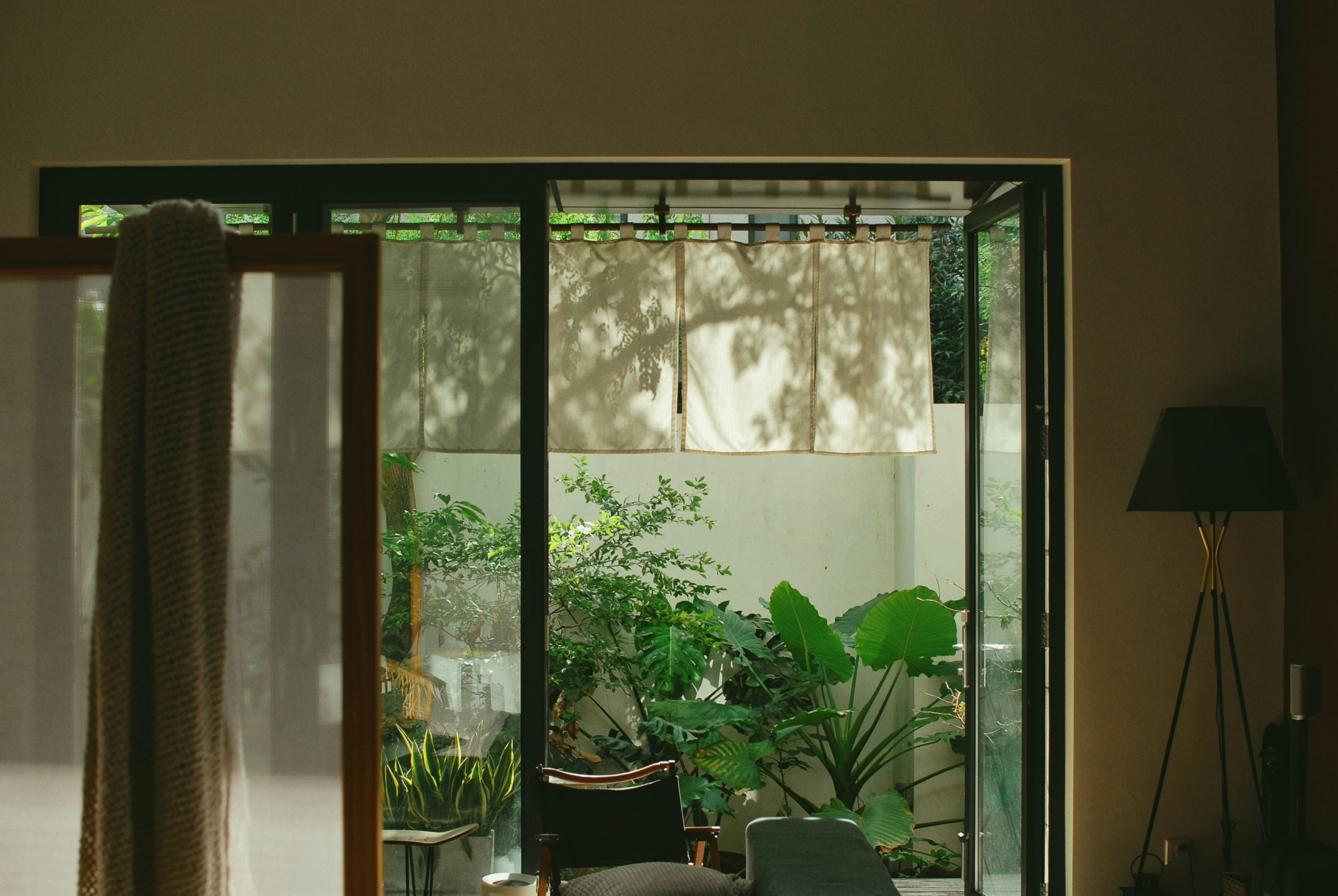 Open glass doors reveal a lush green courtyard garden.