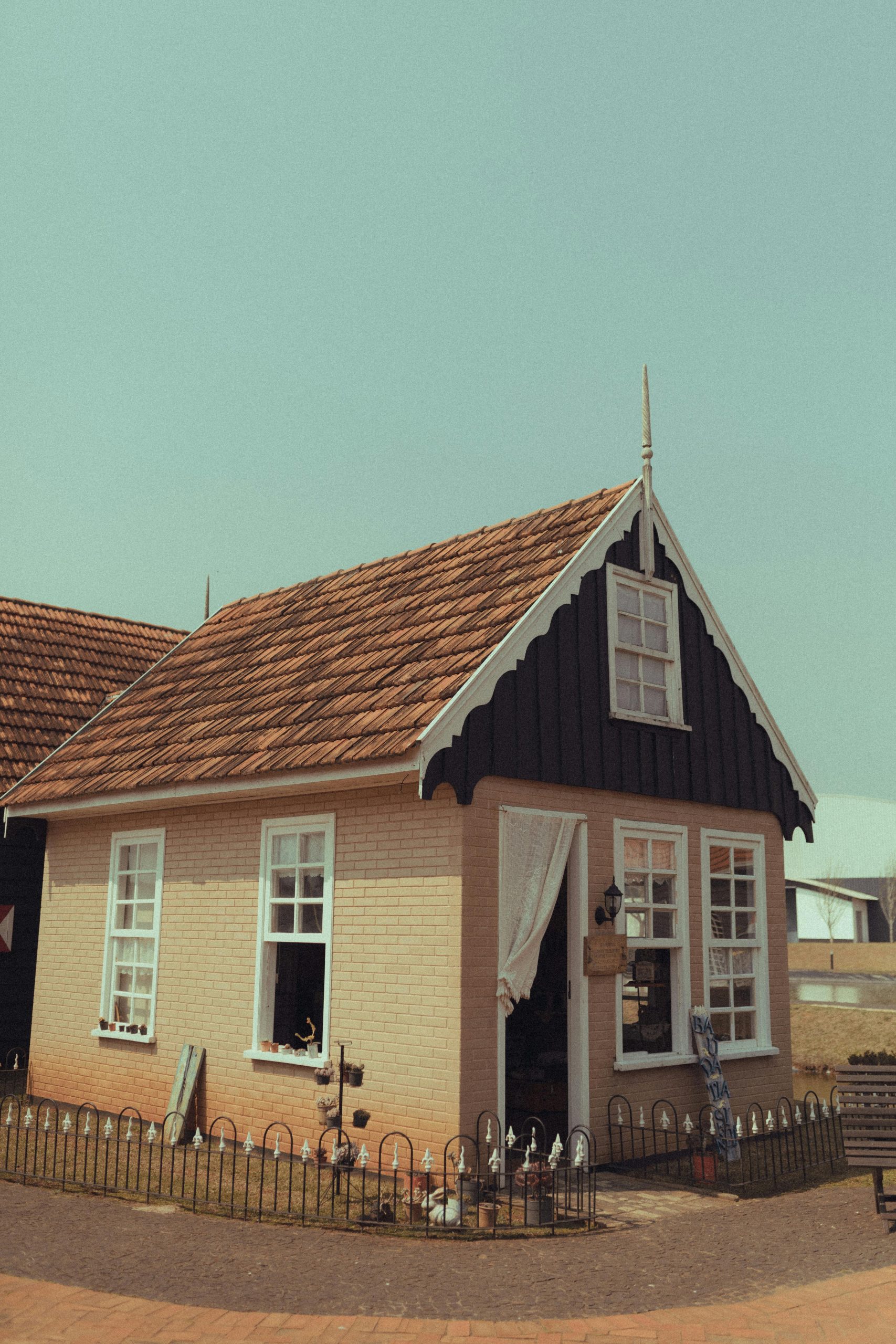 Quaint bungalow with a rustic facade and red roof in bright daylight.