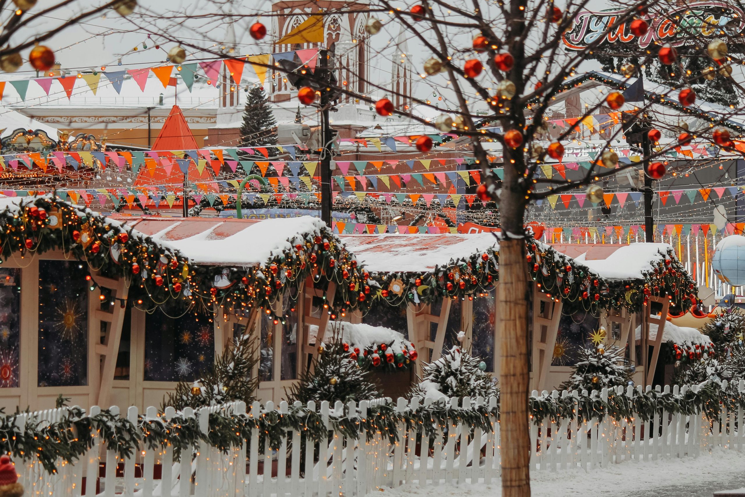 Snow-covered festive market adorned with colorful banderitas and Christmas lights, creating a vibrant winter scene.