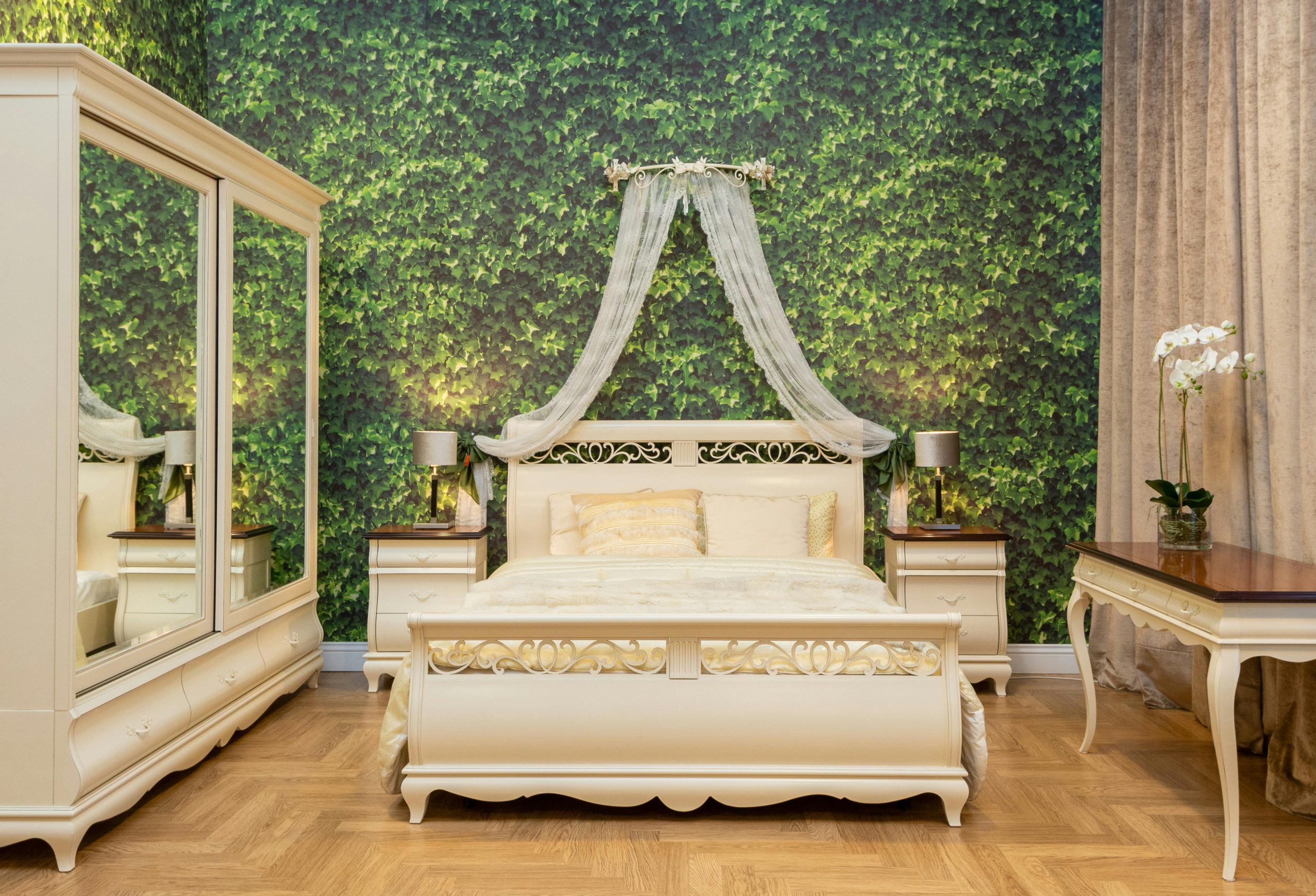 Sophisticated bedroom design featuring a lush green accent wall, elegant white furniture, and natural wooden floors.