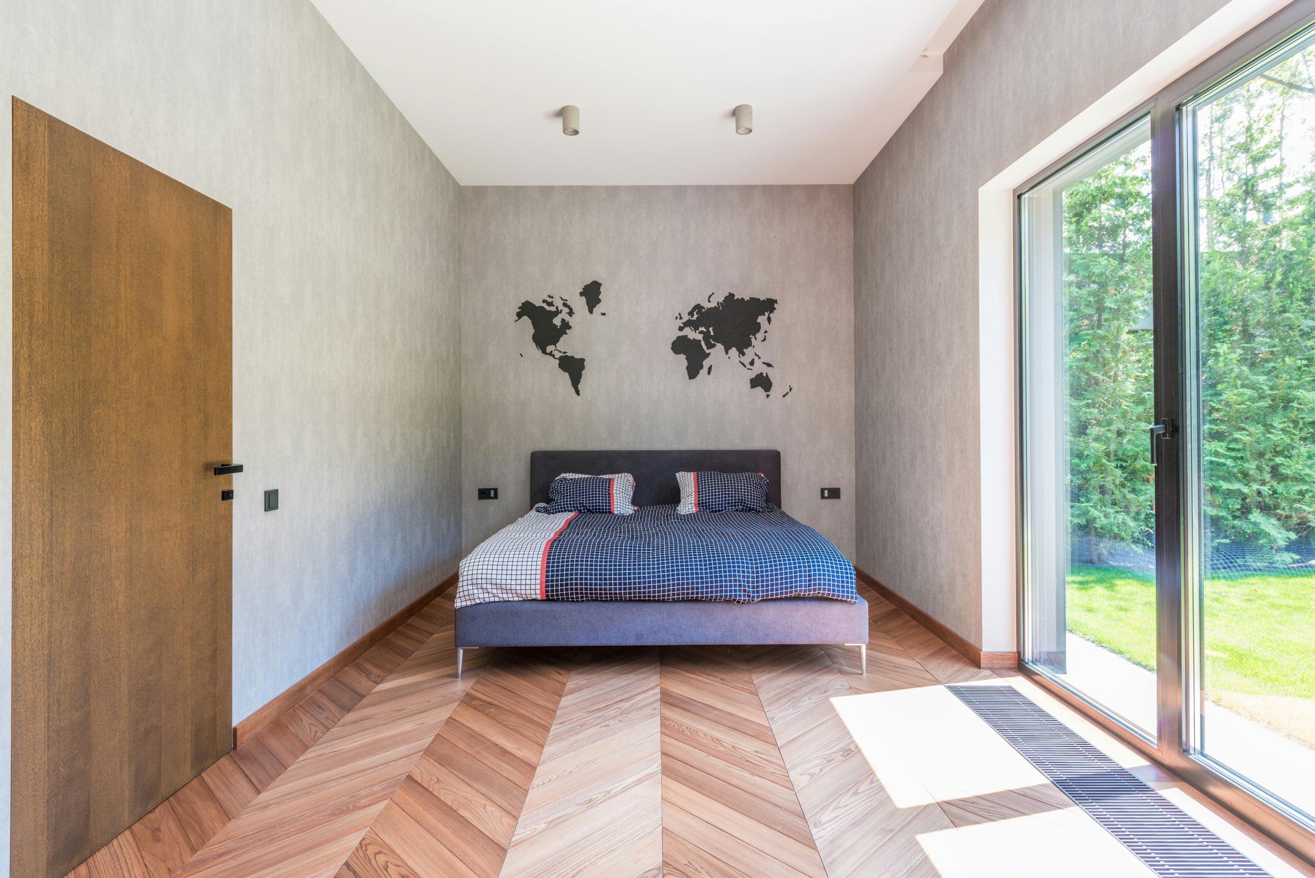 Spacious and minimalist bedroom with a world map wall decor, featuring natural light and modern design elements.
