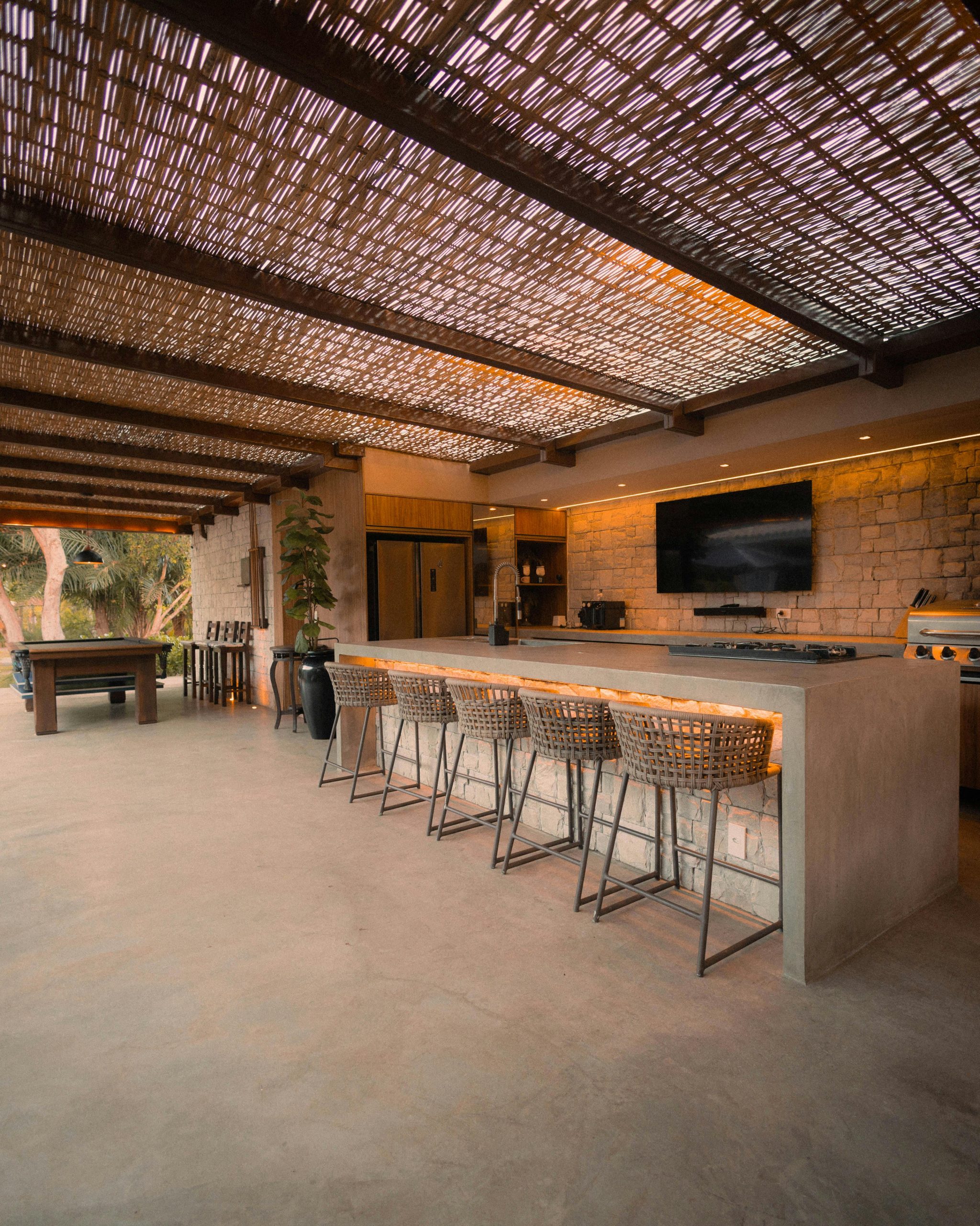 Spacious outdoor kitchen with a bar, pool table, and modern design elements.
