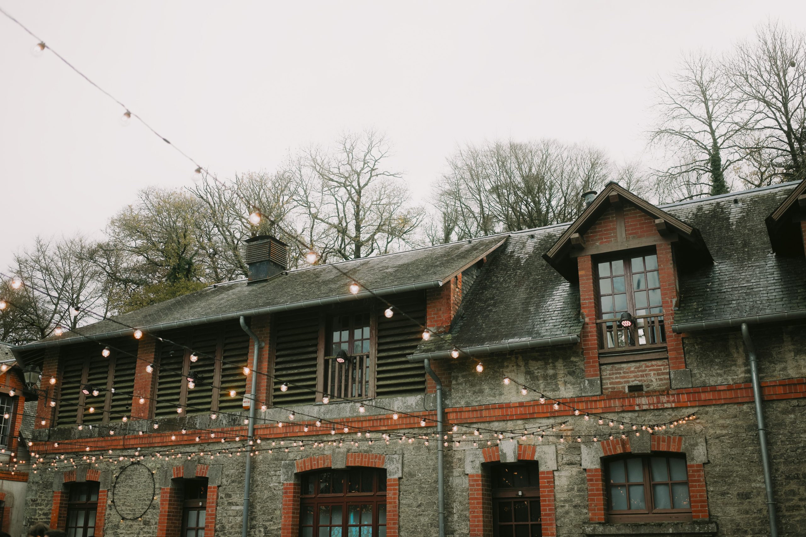 Stone building with string lights and bare trees