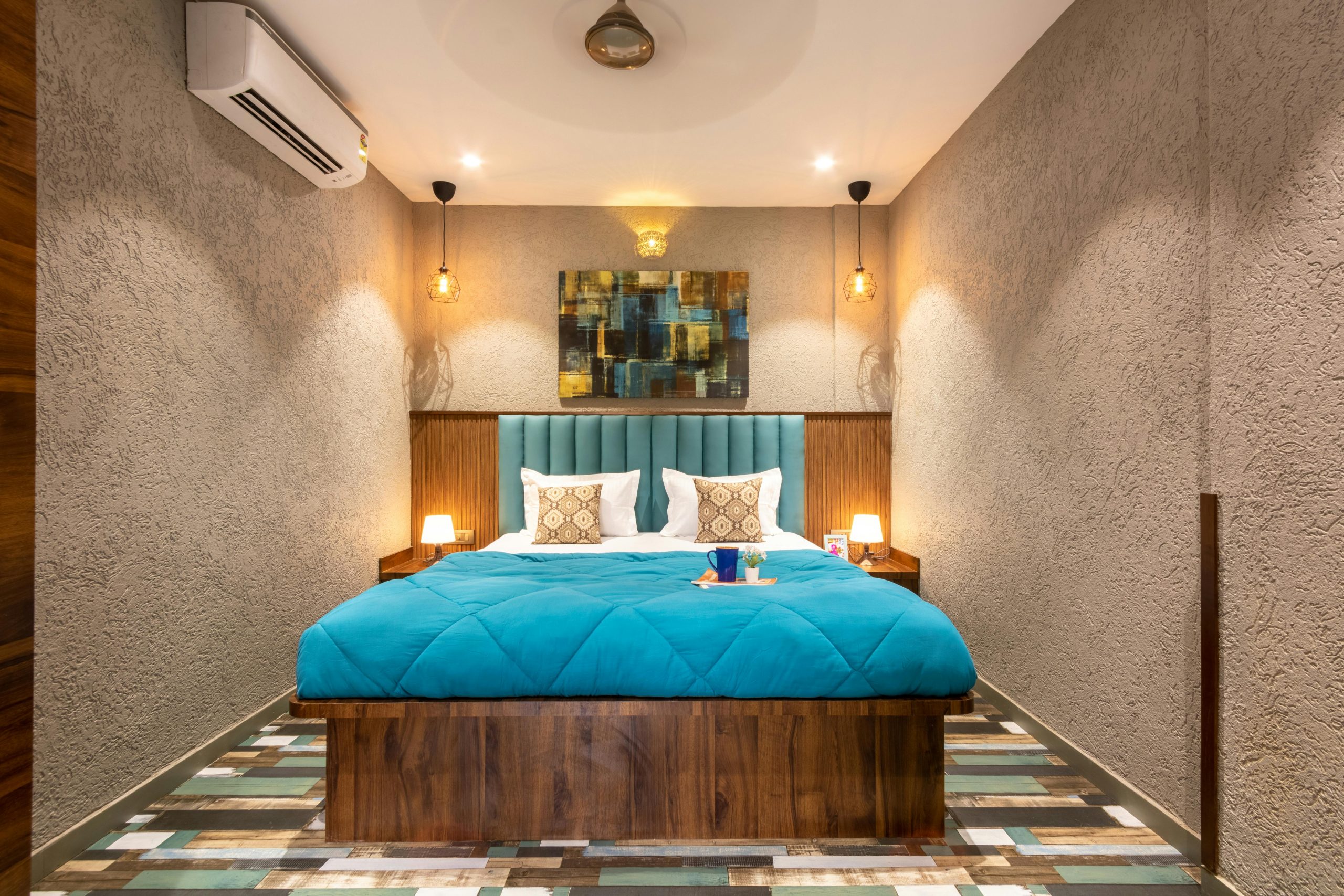 Stylish and cozy modern bedroom with vibrant blue bedding and artistic wall decor, perfect for a relaxing stay.