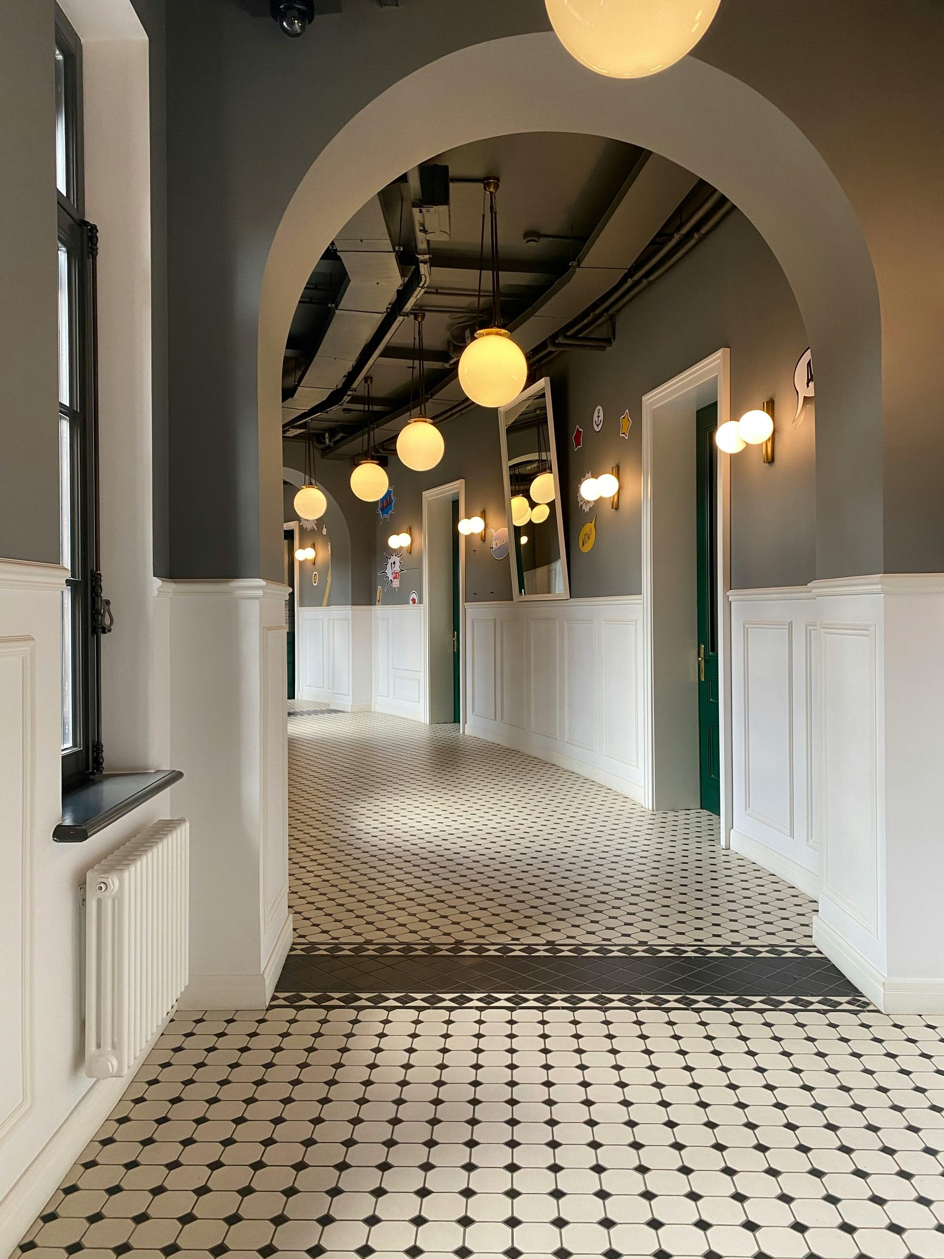 Stylish corridor with arched doorways and hanging lights, featuring classic design elements.