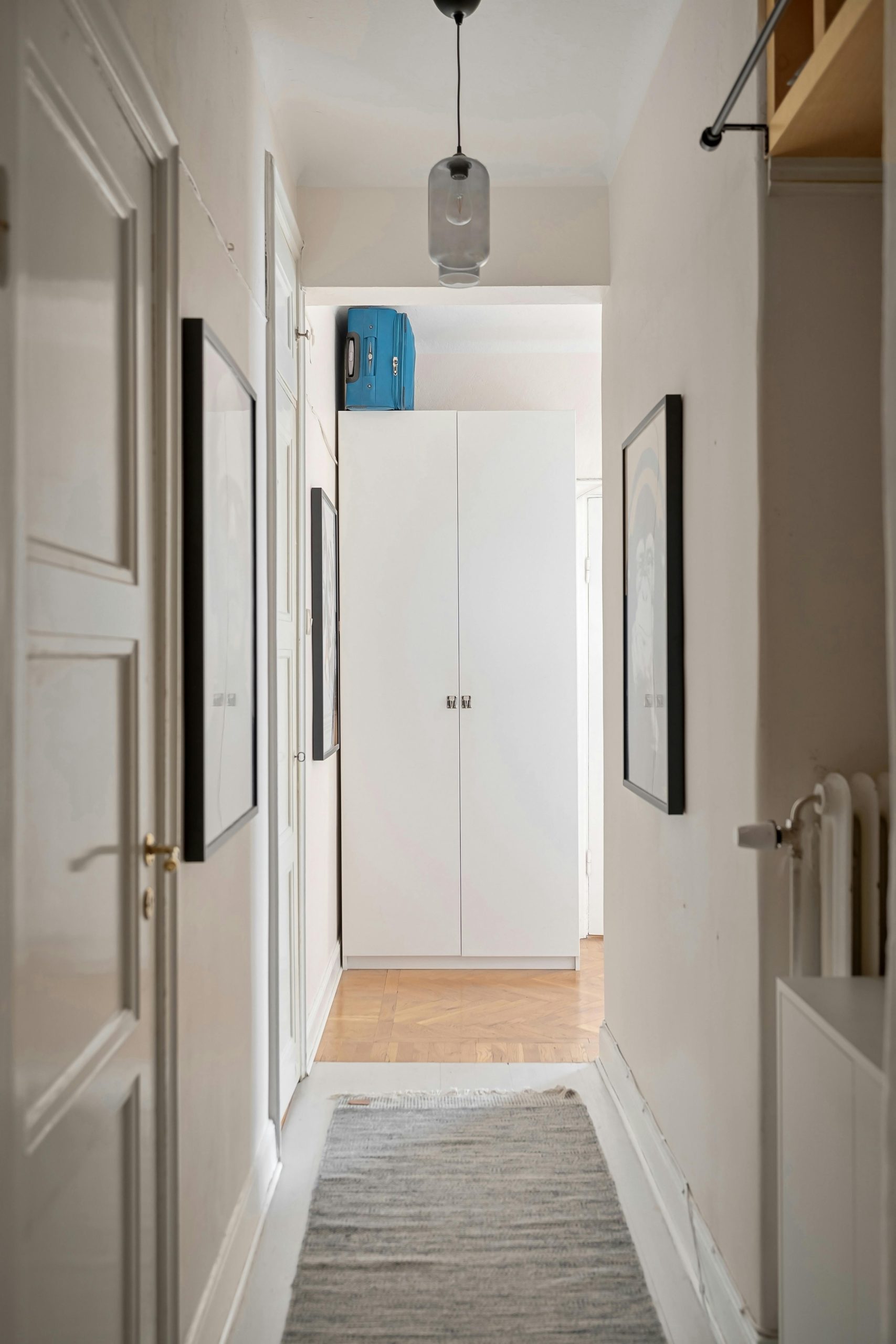Stylish corridor with white wardrobe, art, and modern lighting.