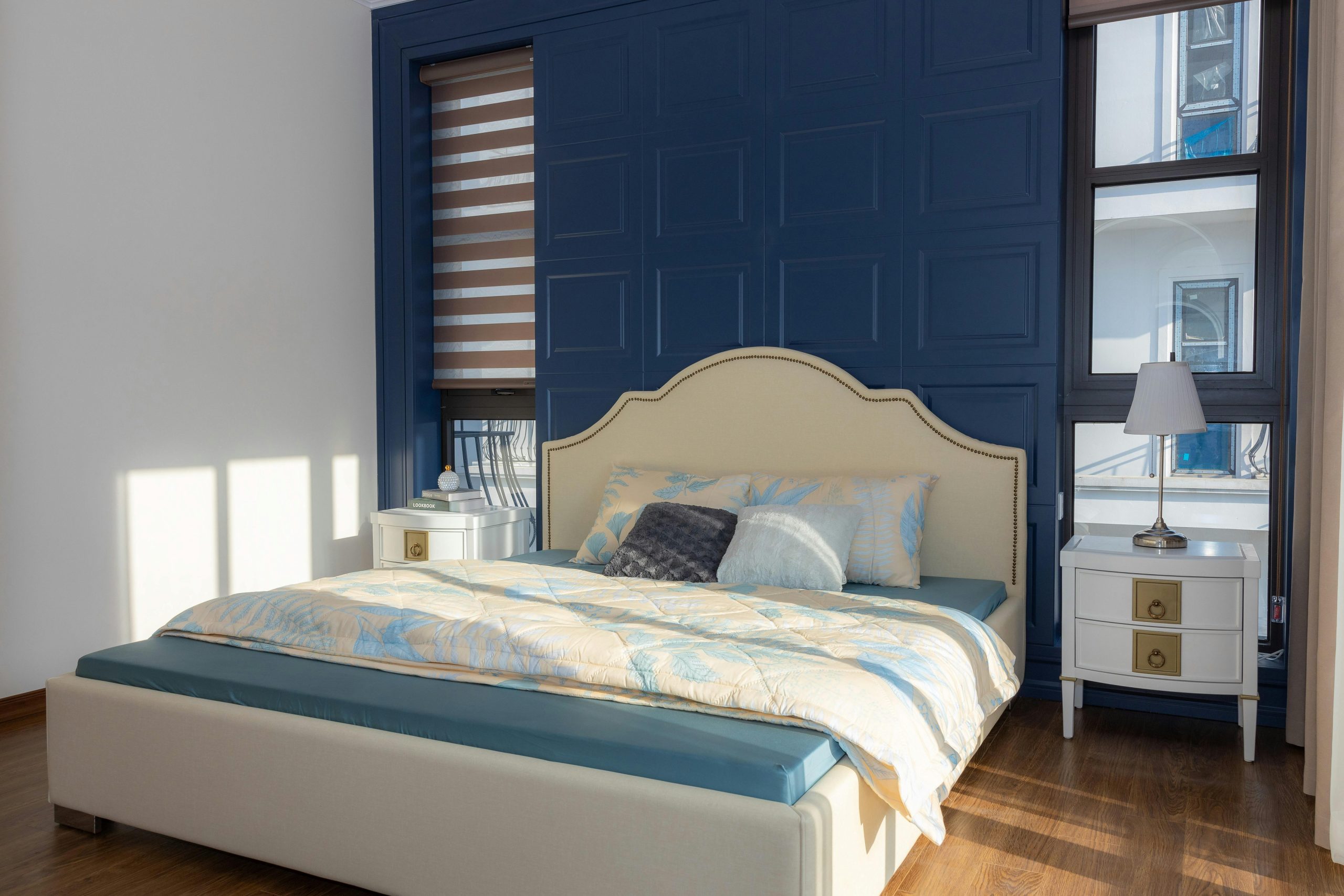 Sunlit modern bedroom with blue accent wall and elegant decor, creating a cozy atmosphere.