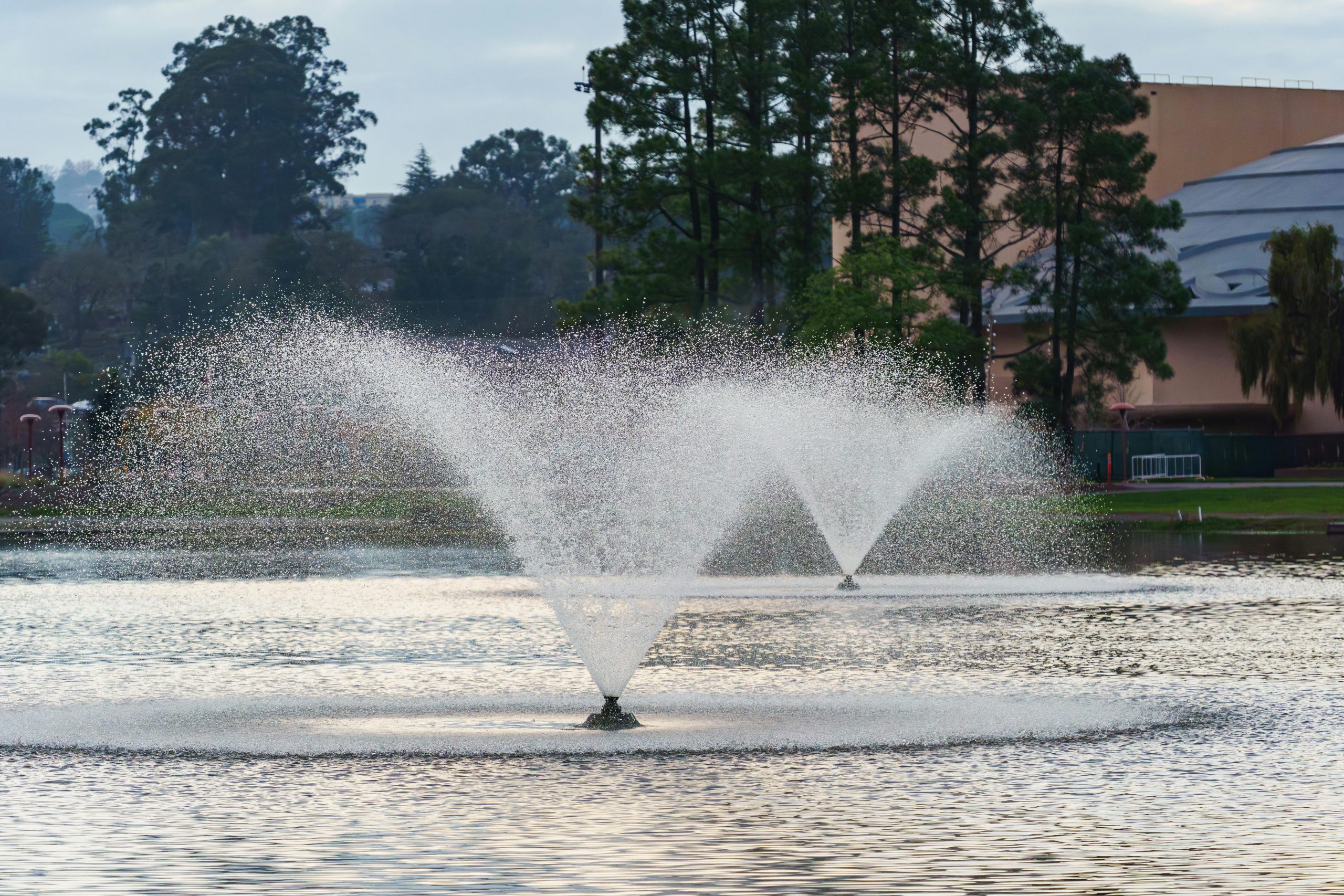 Twin water fountains gracefully spray water in a serene park environment.