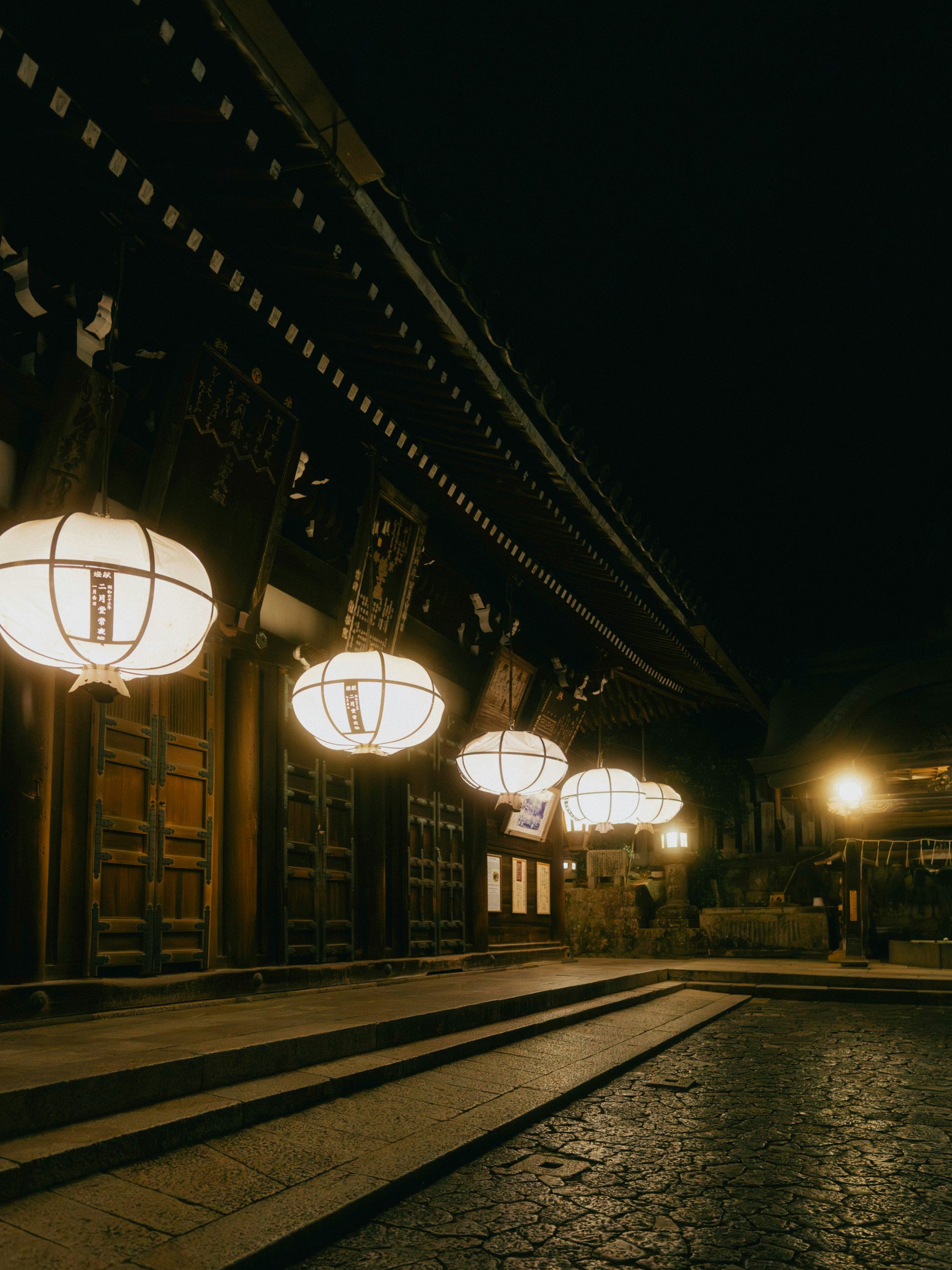 White lanterns illuminate a dark street at night.