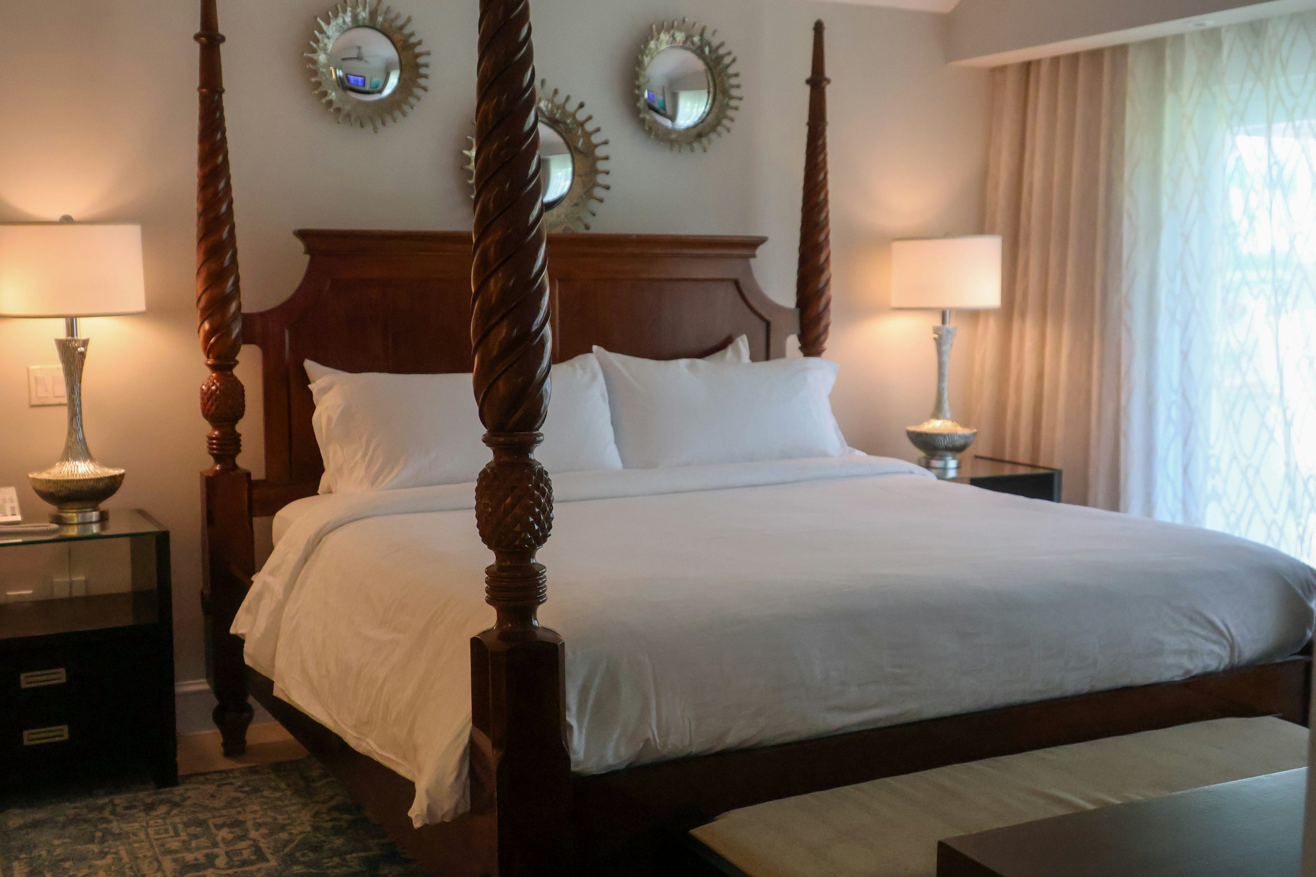 A bedroom with a four post bed and two lamps