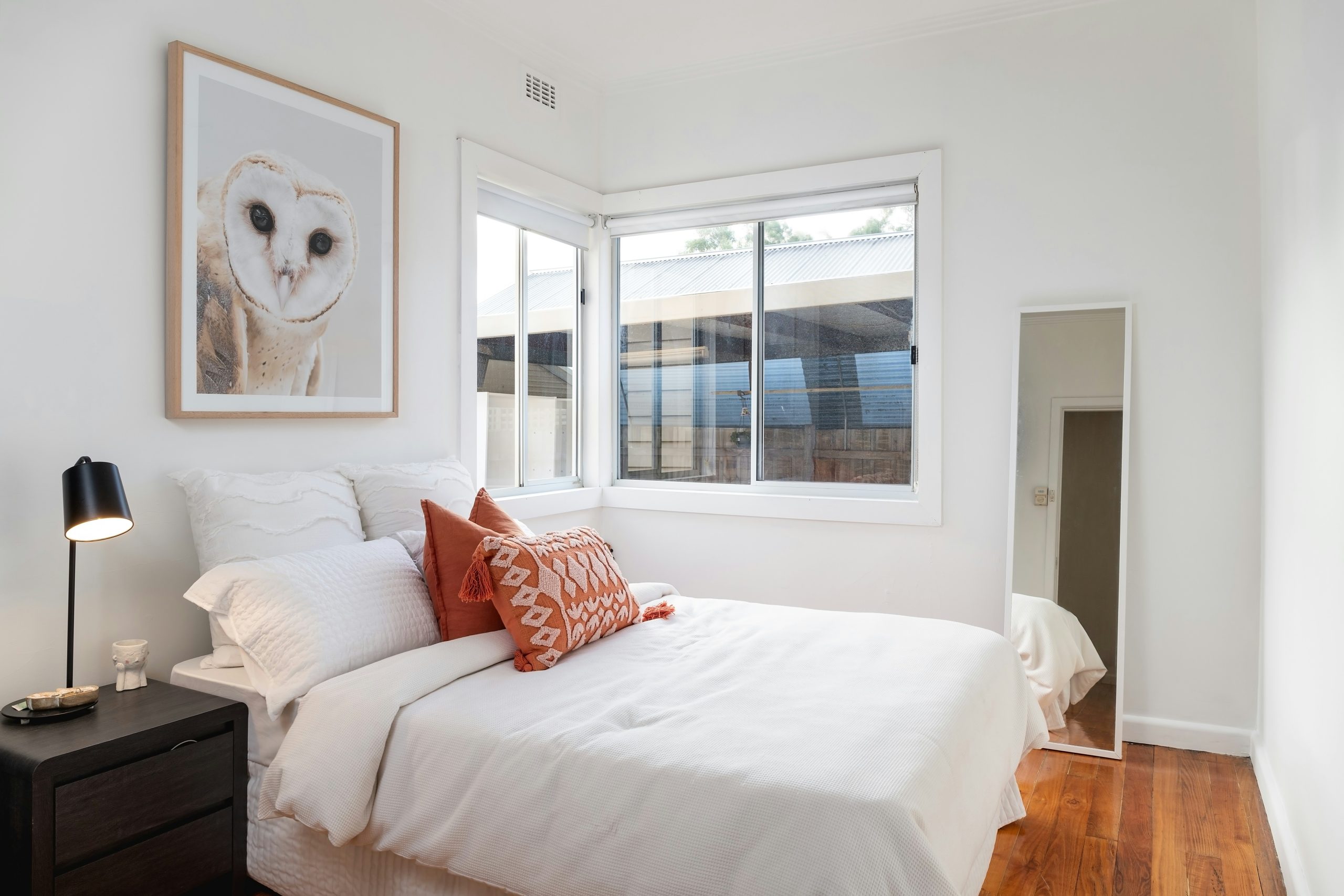 a bedroom with a white bed and a painting on the wall
