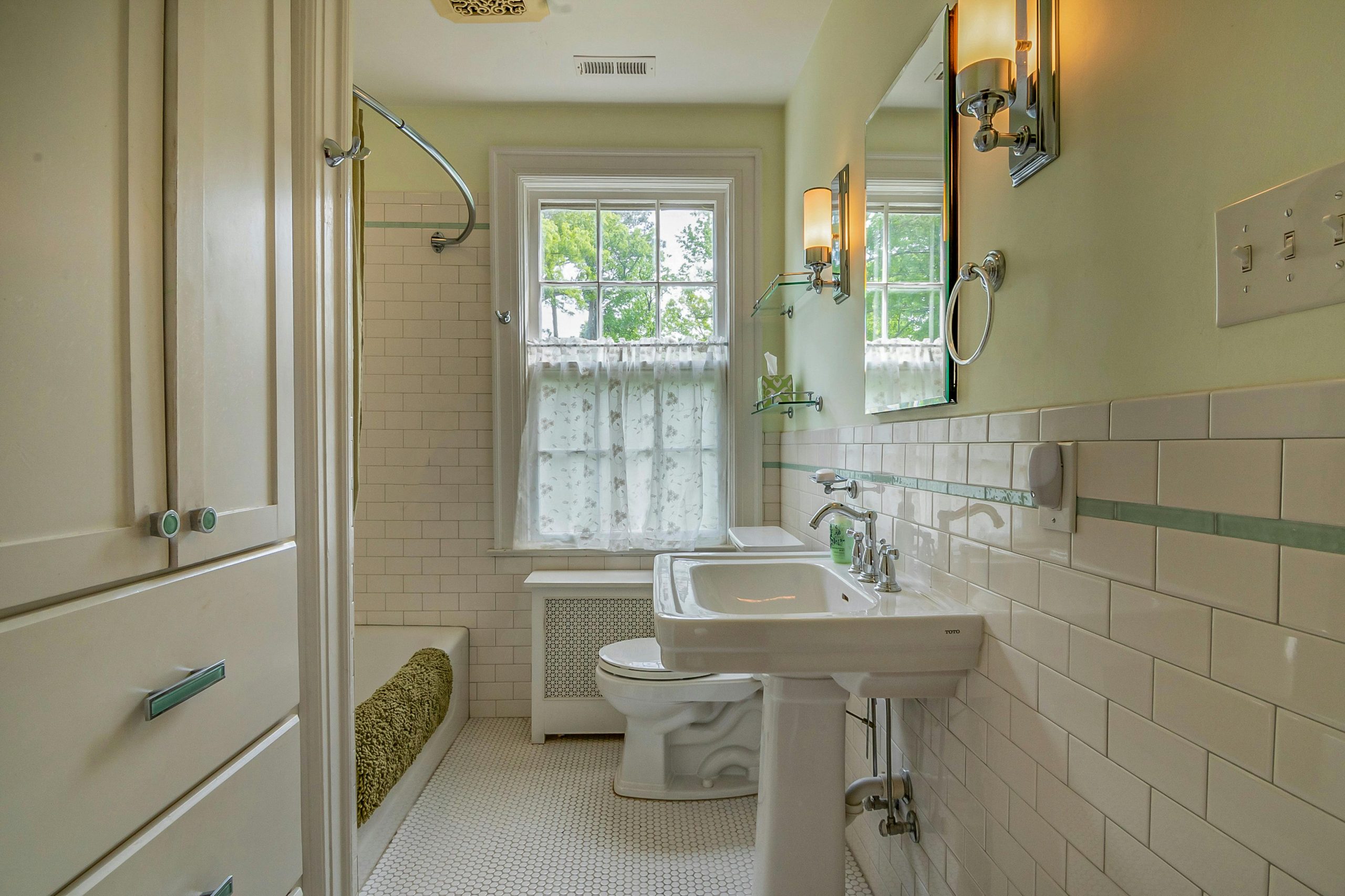 A bright and elegant bathroom featuring a window, sink, and stylish tiles for a refreshing ambiance.