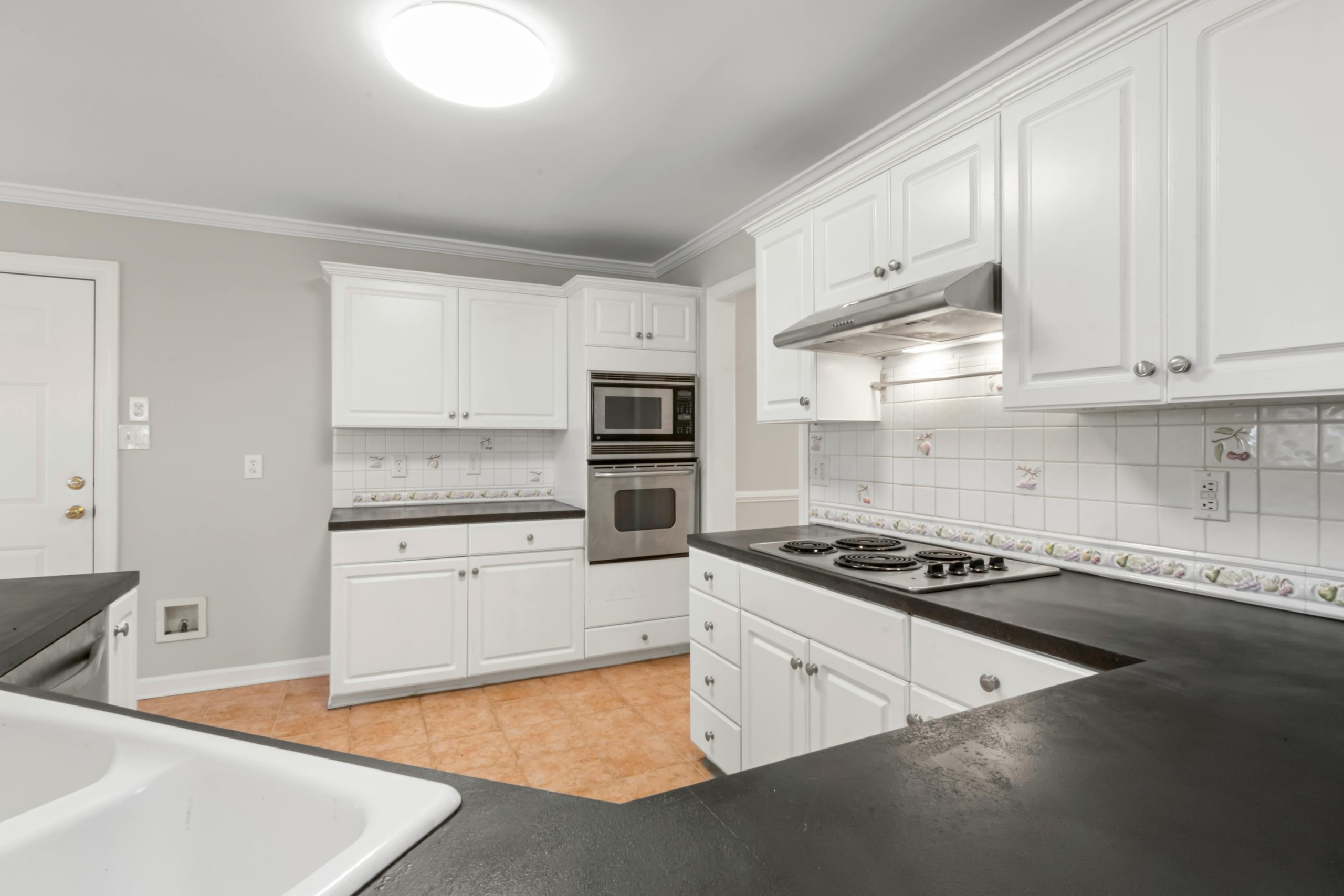 A clean and modern kitchen featuring white cabinets and black countertops with elegant lighting.