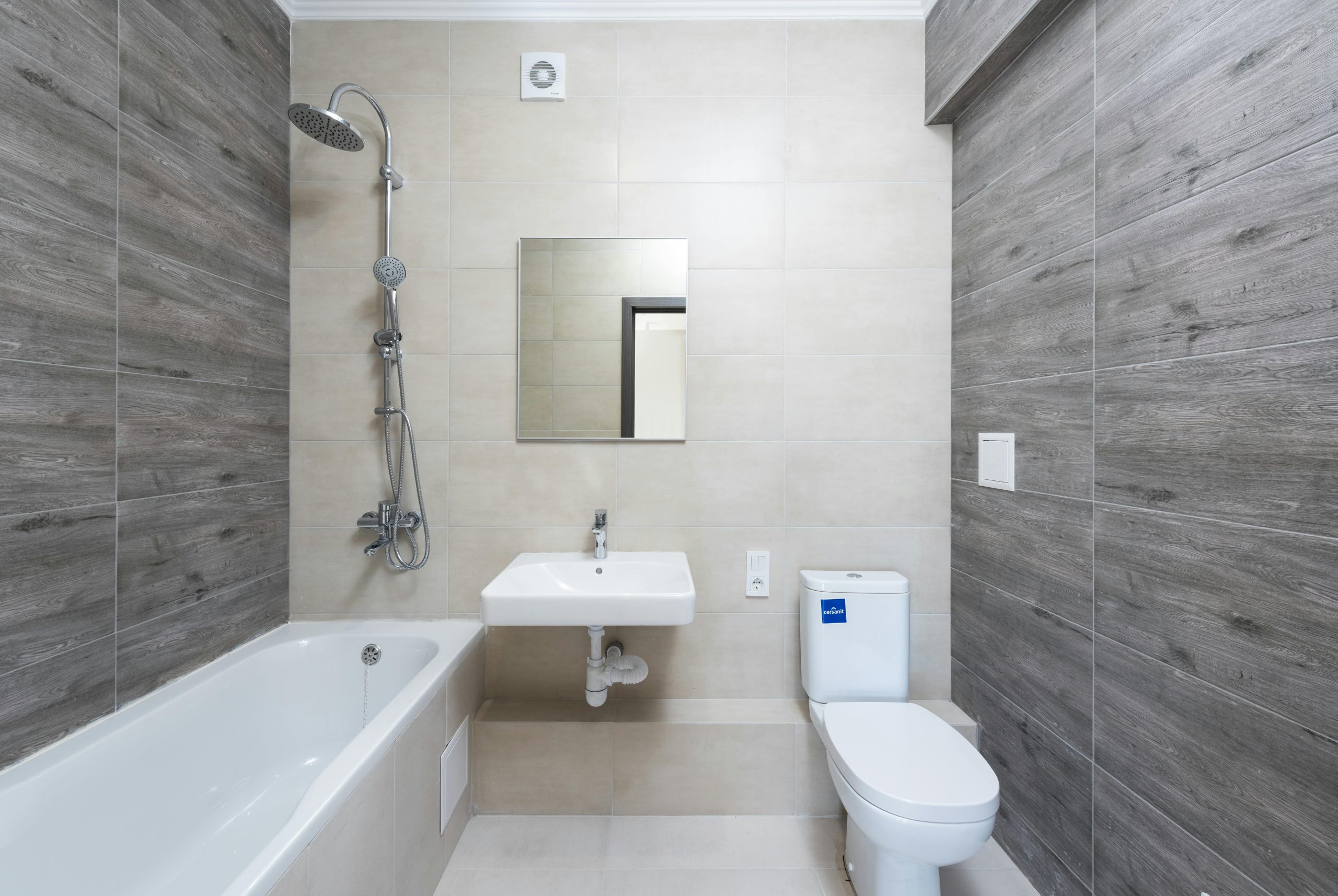 A contemporary bathroom features a bathtub, sink, and toilet with wood accents.
