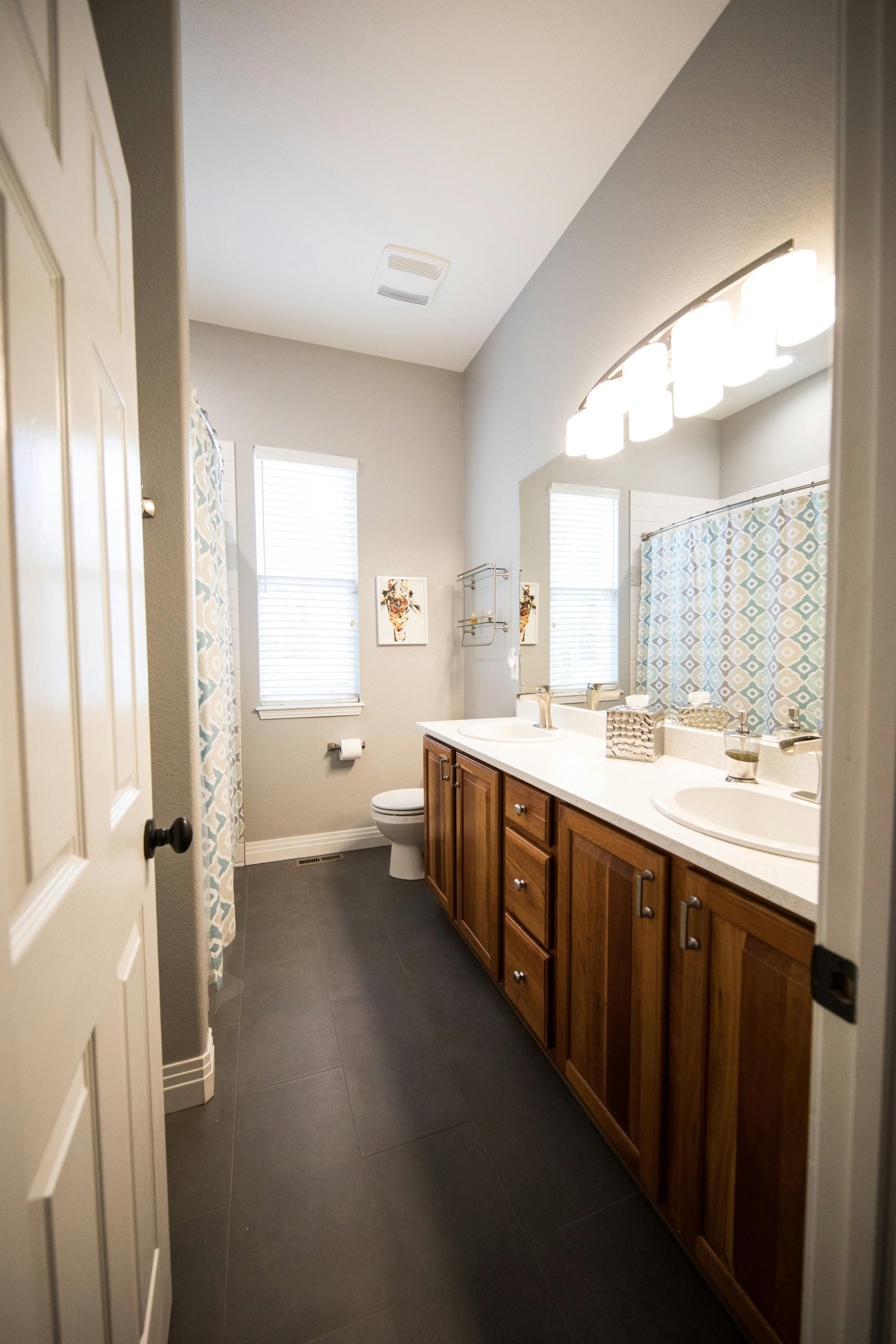 A contemporary bathroom featuring wooden cabinets, a large mirror, and sleek design.