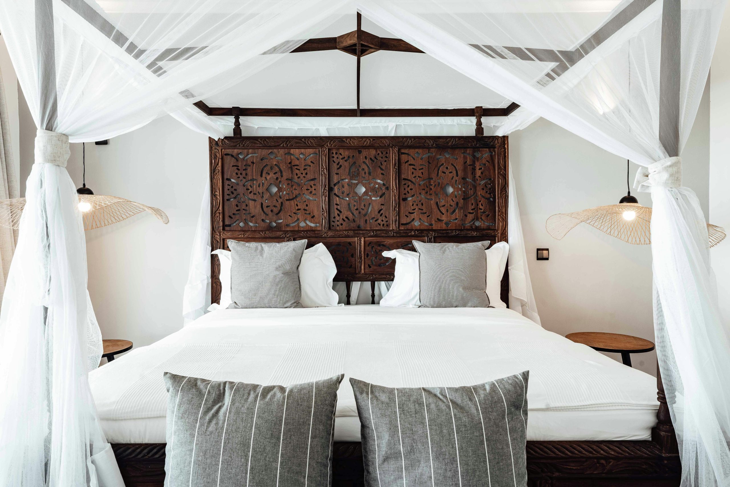 A cozy and contemporary bedroom with a stylish canopy bed featuring carved wood details.