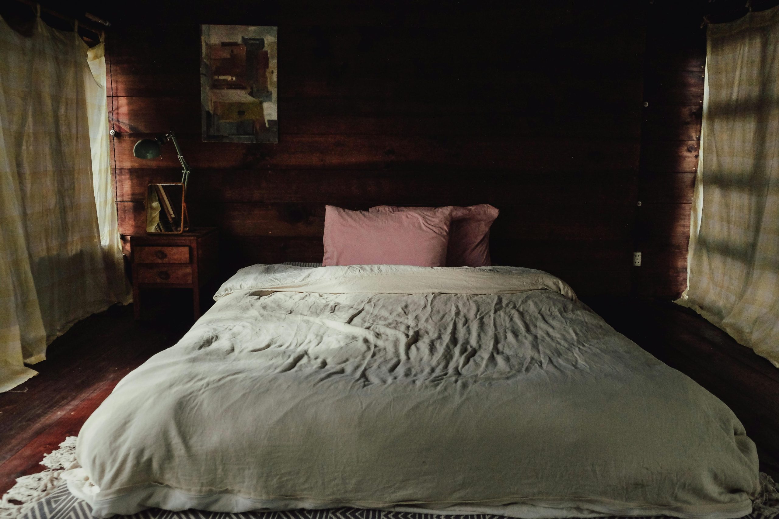 A cozy and rustic bedroom with wooden walls, plush bedding, and soft lighting.