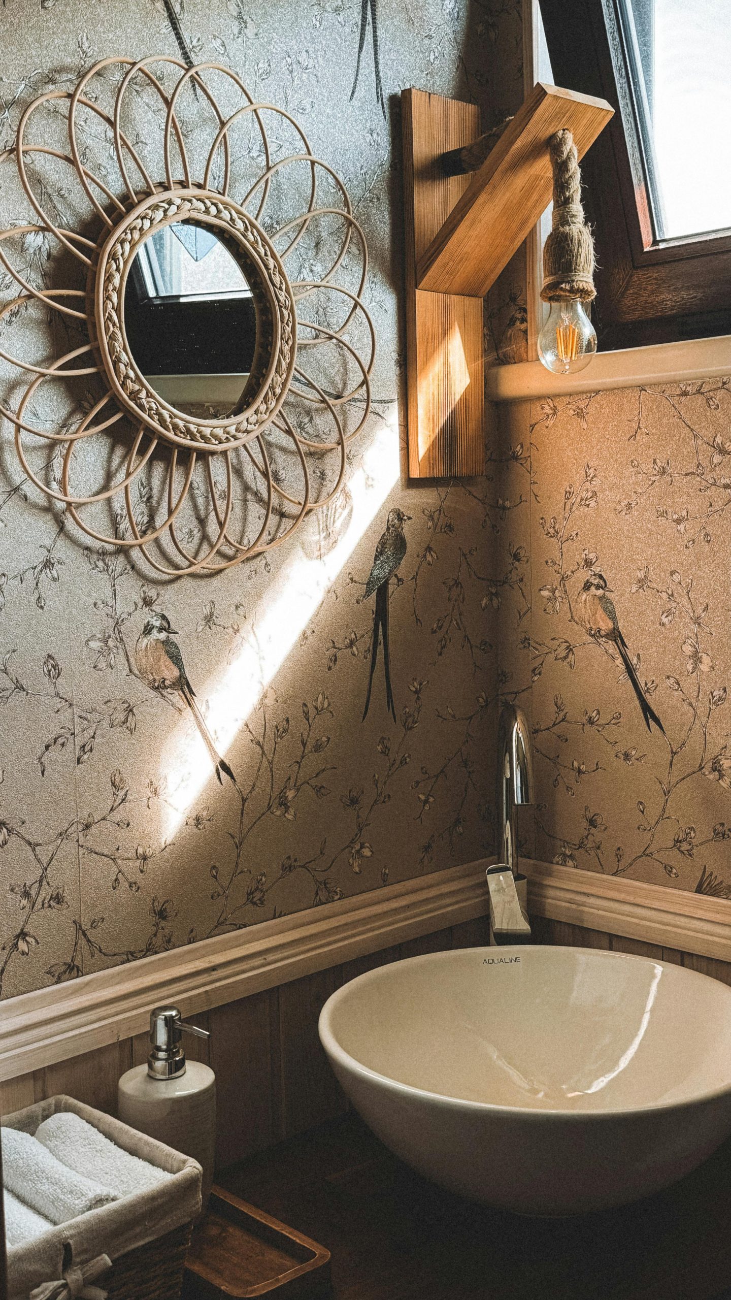 A cozy rustic bathroom featuring a wicker mirror, wall decor, and natural light.