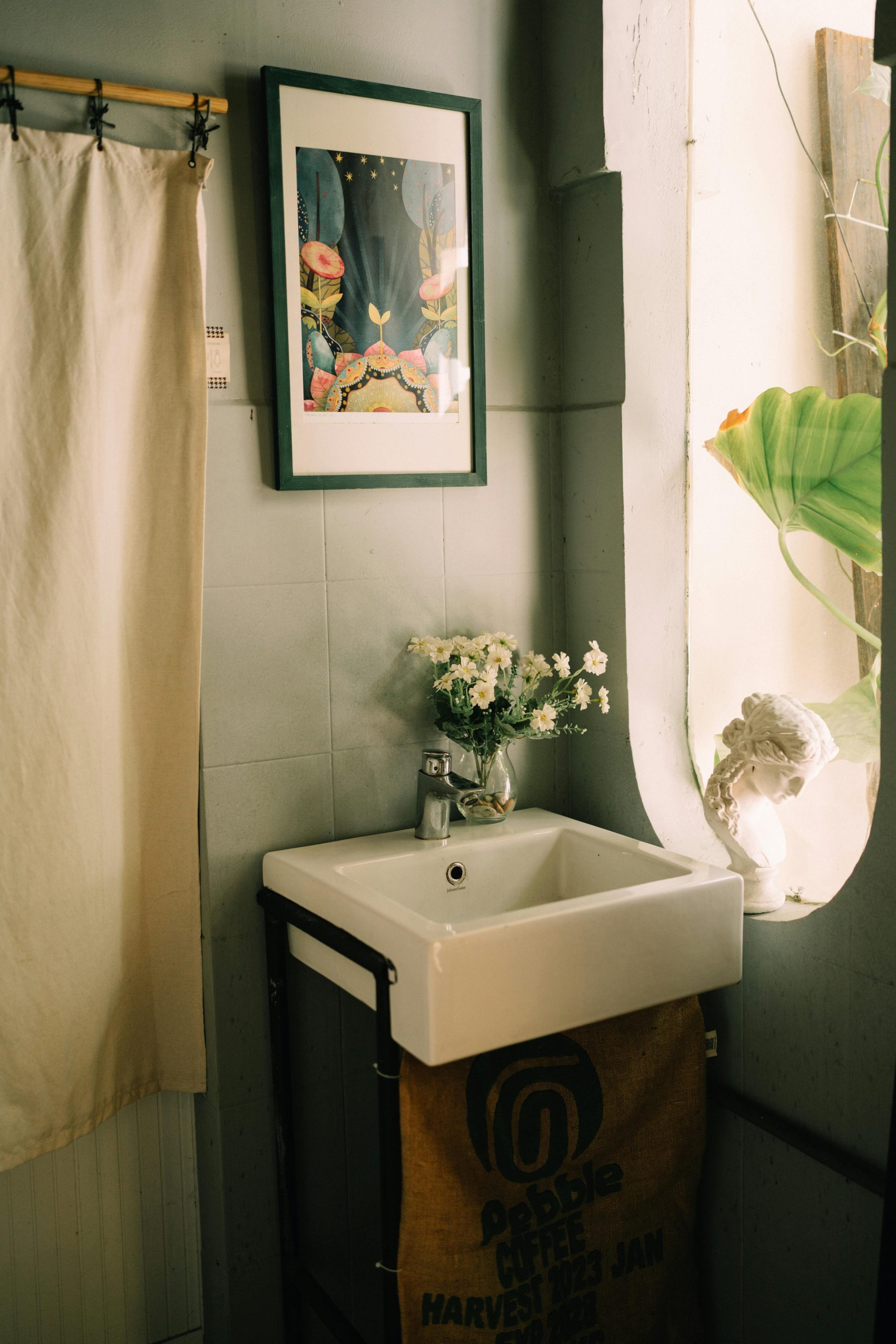 A minimalist bathroom with a sink, floral decor, and artistic wall art.